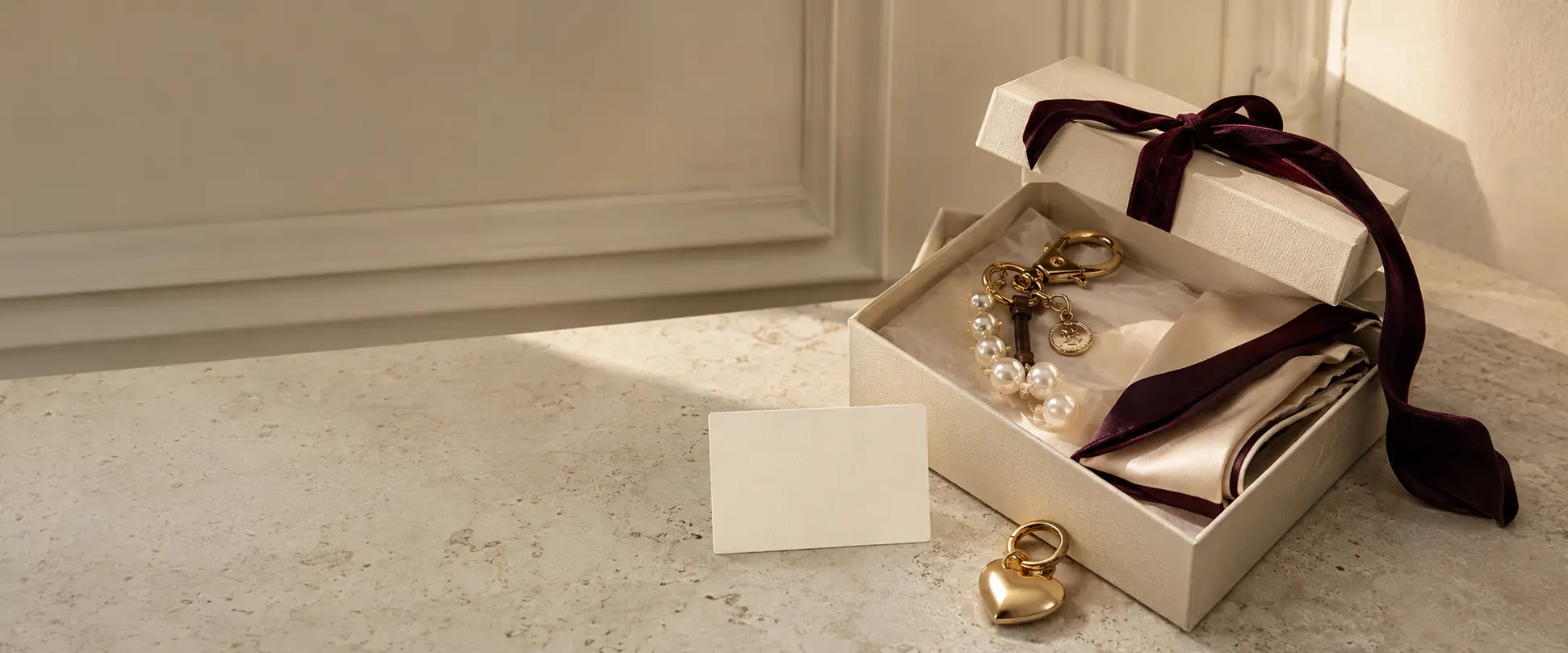 Ivory gift box with pearl bag charm, gold heart charm and burgundy silk twilly.