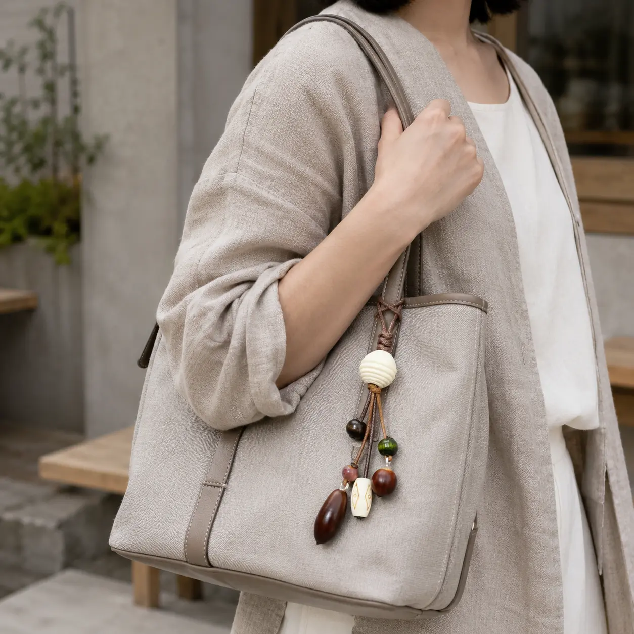 Wabi-sabi beaded bag charm styledon a greige tote in a minimalistJapanese street scene