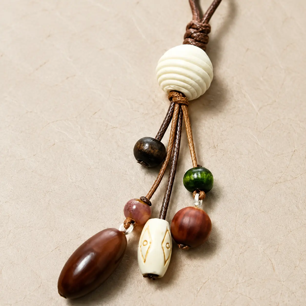 Close-up of textured cord, ridged ivory bead and artisan-style beads on a bag charm