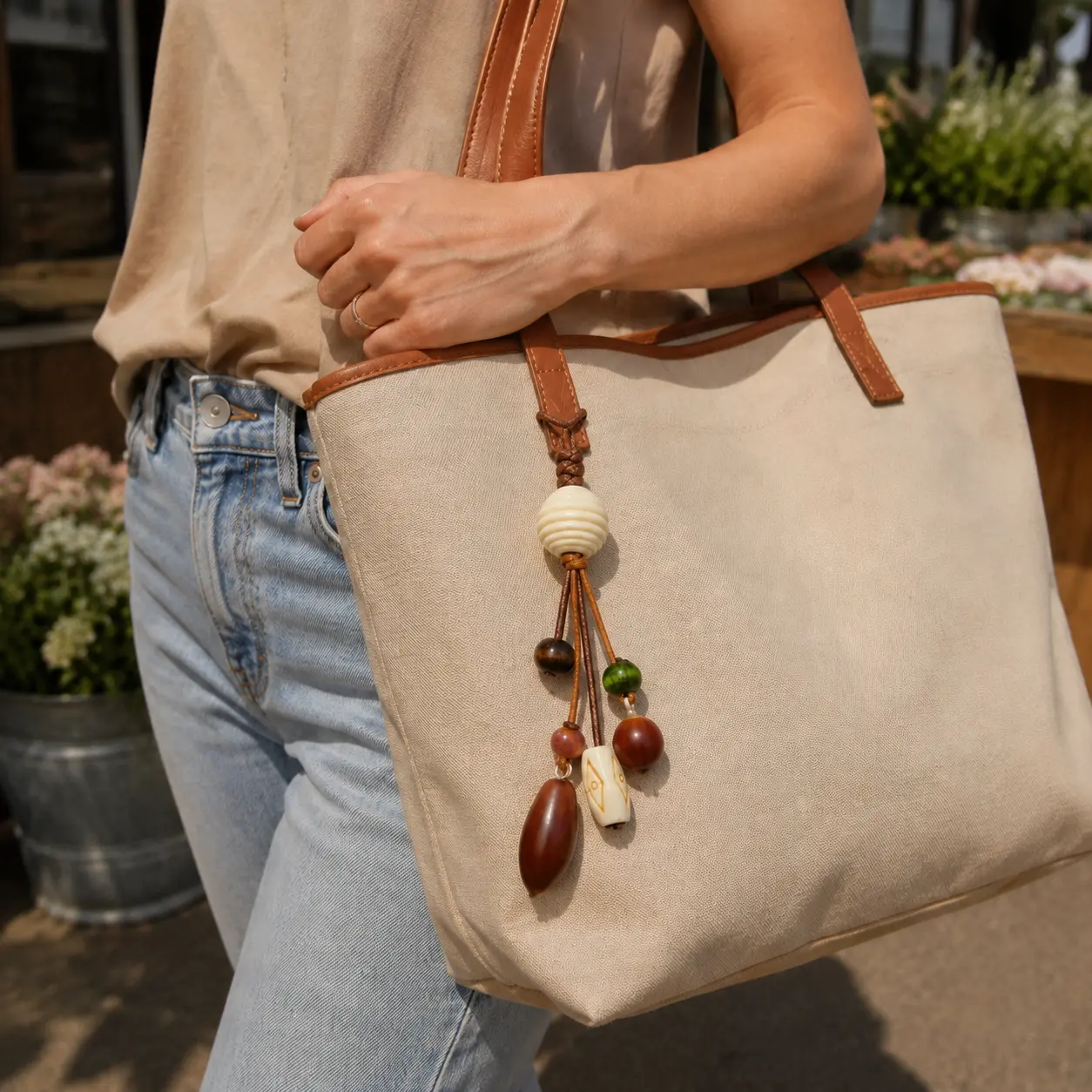 Natural-tone beaded bag charm styled on a canvas tote for an American weekend look