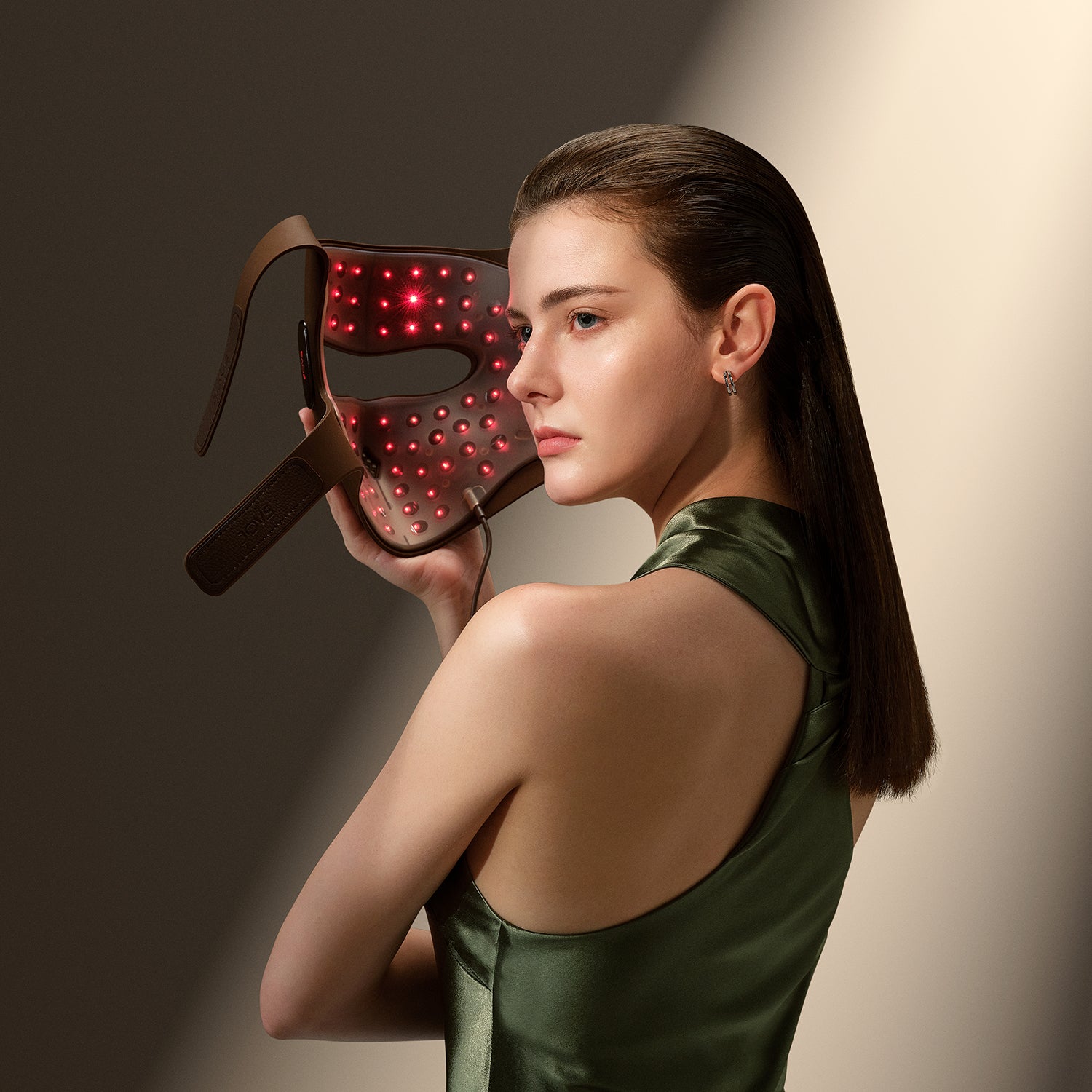 Woman holding illuminated 4D laser light therapy mask
