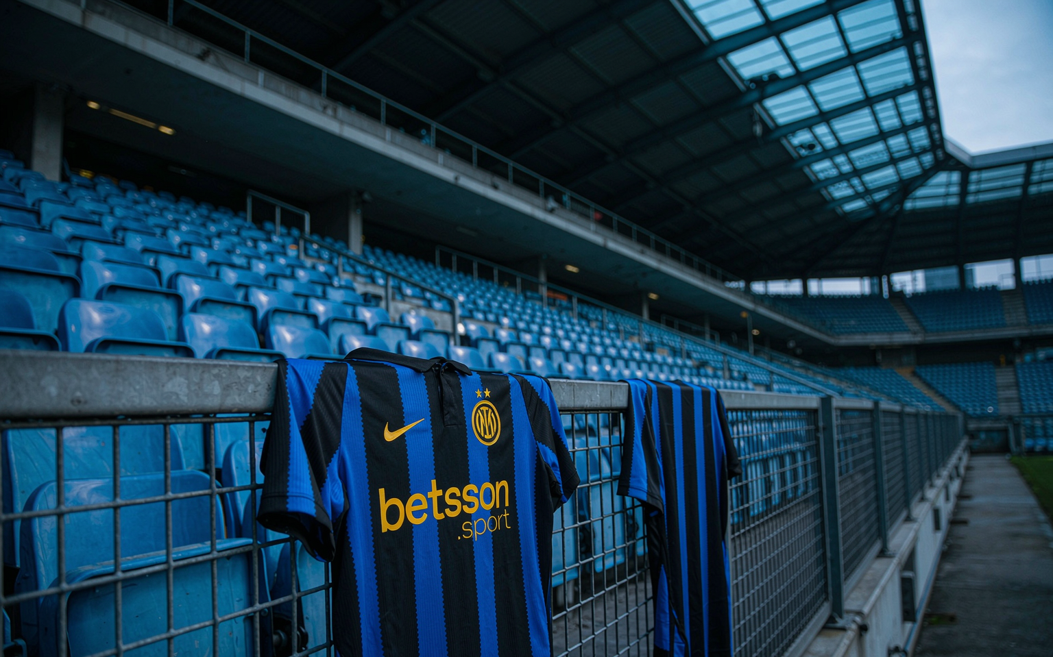Empty floodlit stadium stand at dusk with a football shirt draped over the barrier
