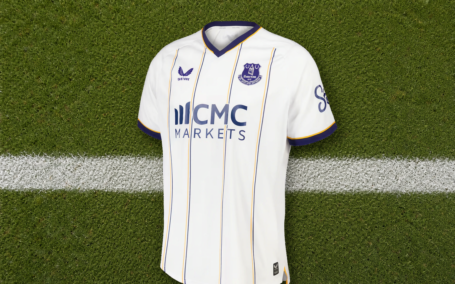 Overhead view of a football shirt laid flat on mown grass beside a touchline