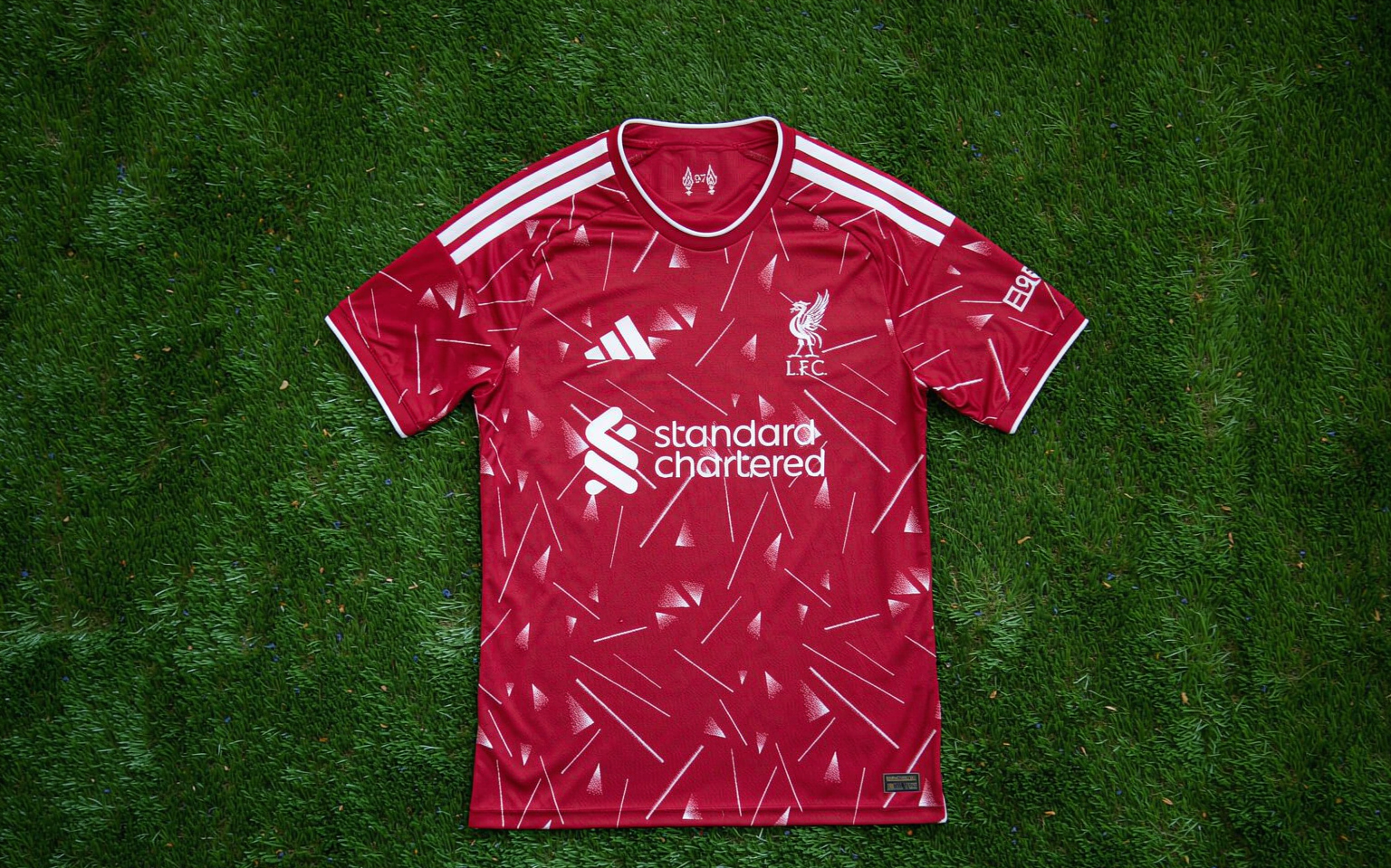 Overhead view of a football shirt laid flat on freshly mown grass under floodlights