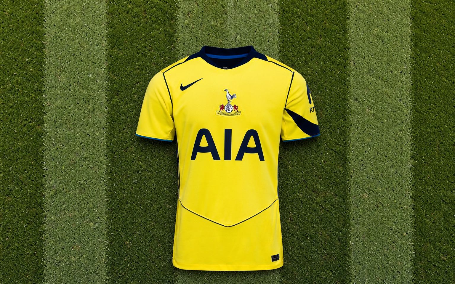 Overhead view of a football shirt laid flat on mown grass inside a stadium