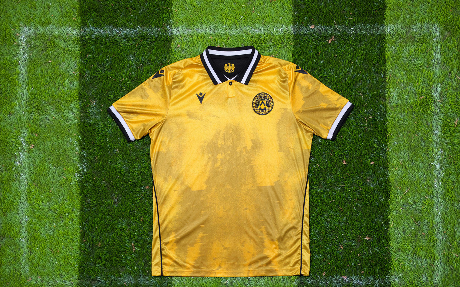 Overhead view of a football shirt laid flat on freshly mown striped grass
