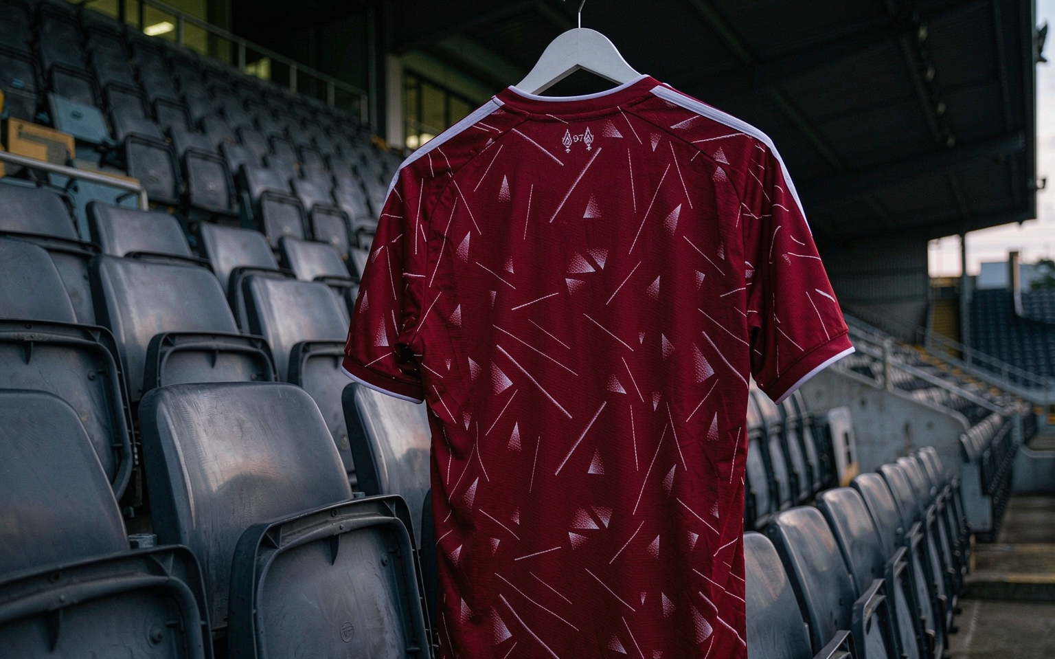Empty floodlit stadium stand at dusk with a football shirt hanging in front of the seating