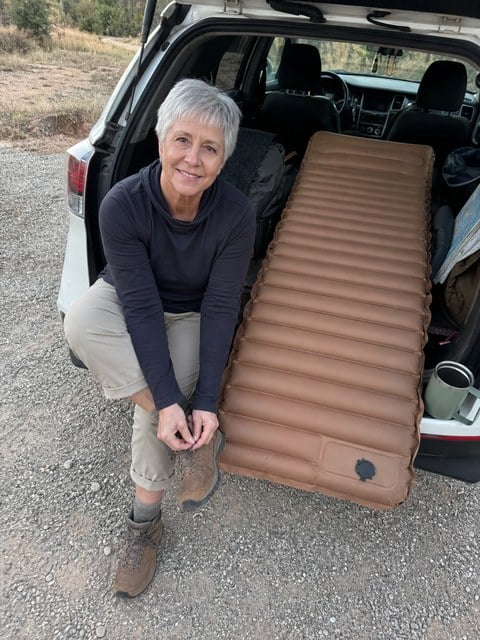Customer-style snapshot of the camping mattress beside an SUV