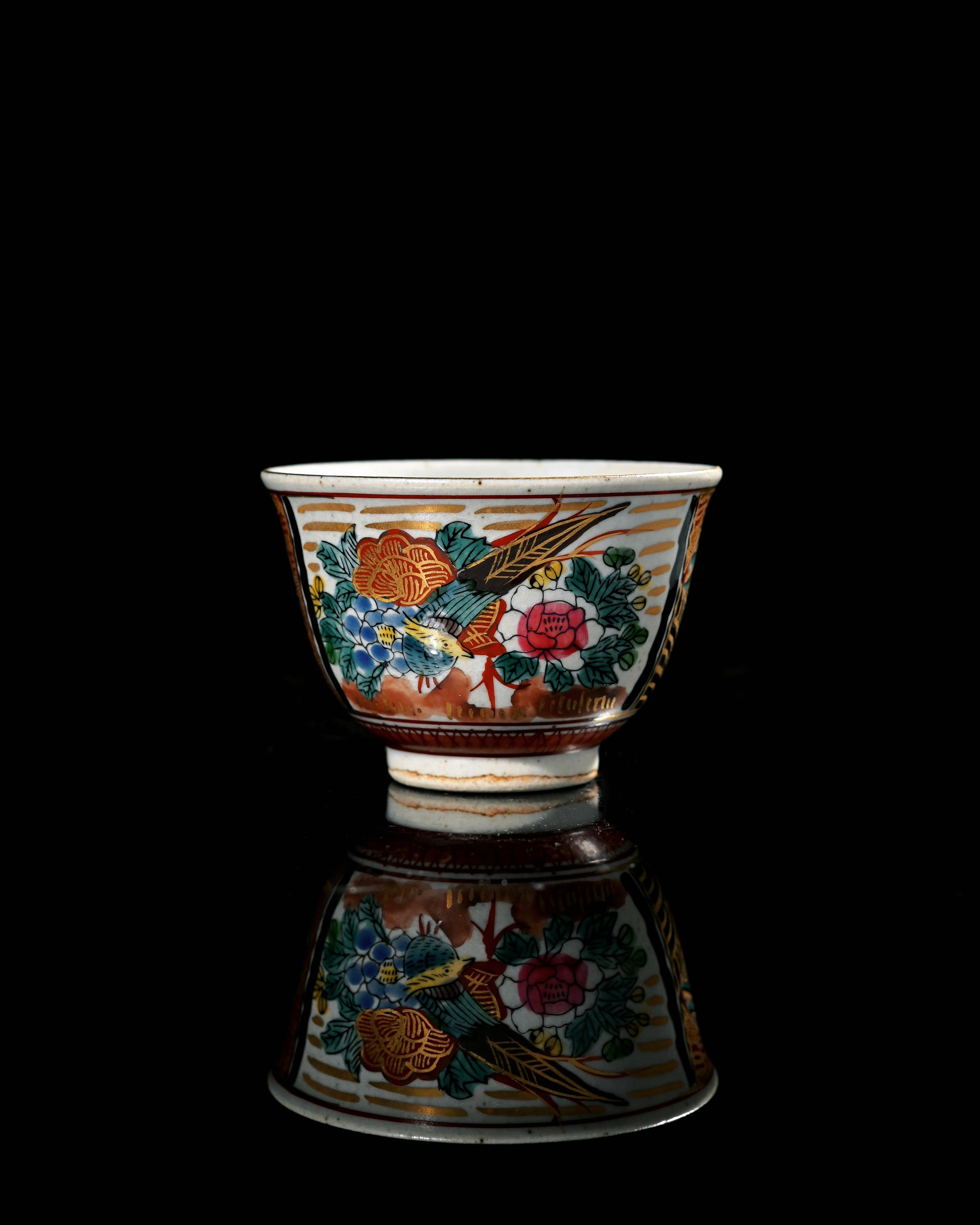 A Kutani tea cup decorated with a Chinese literati figure standing beside a pavilion, surrounded by rocks and distant