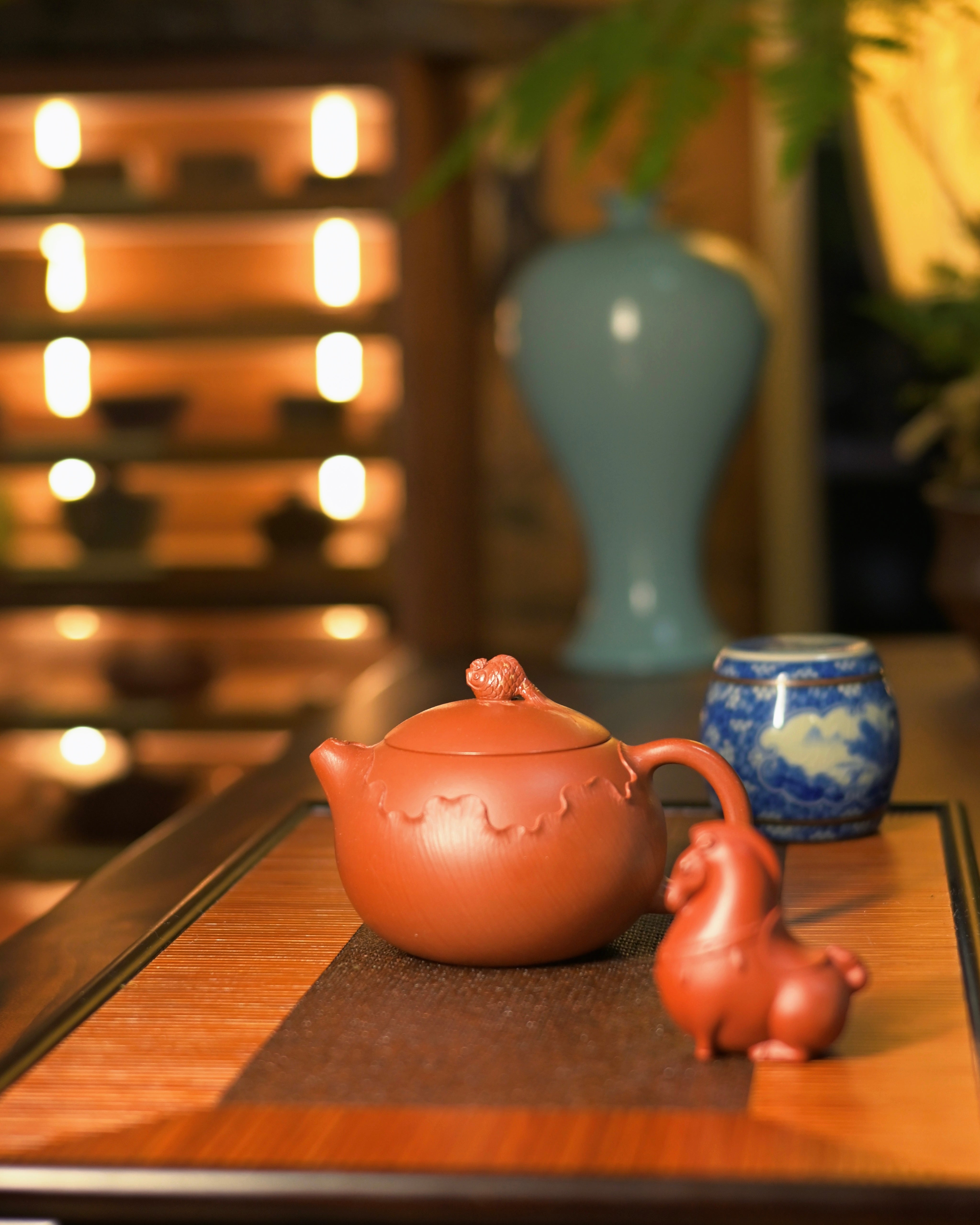 Hand-carved goldfish lid knob showing rounded body, spread tail fins, and engraved eyes on vermilion clay by Kungfuyang