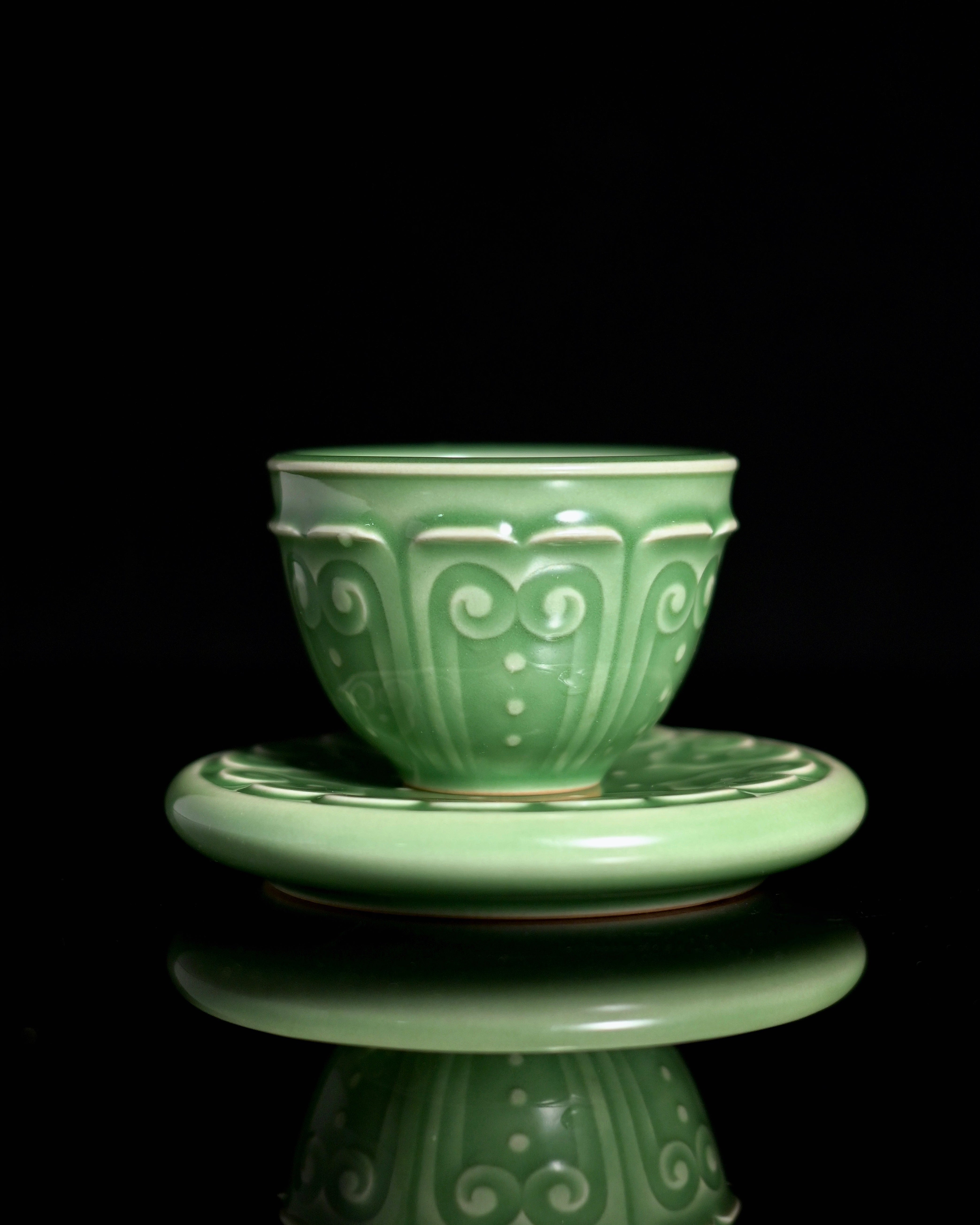 Elegant Longquan celadon teacup with saucer featuring plum green glaze and hand-carved Baoxiang pattern, inspired by Song