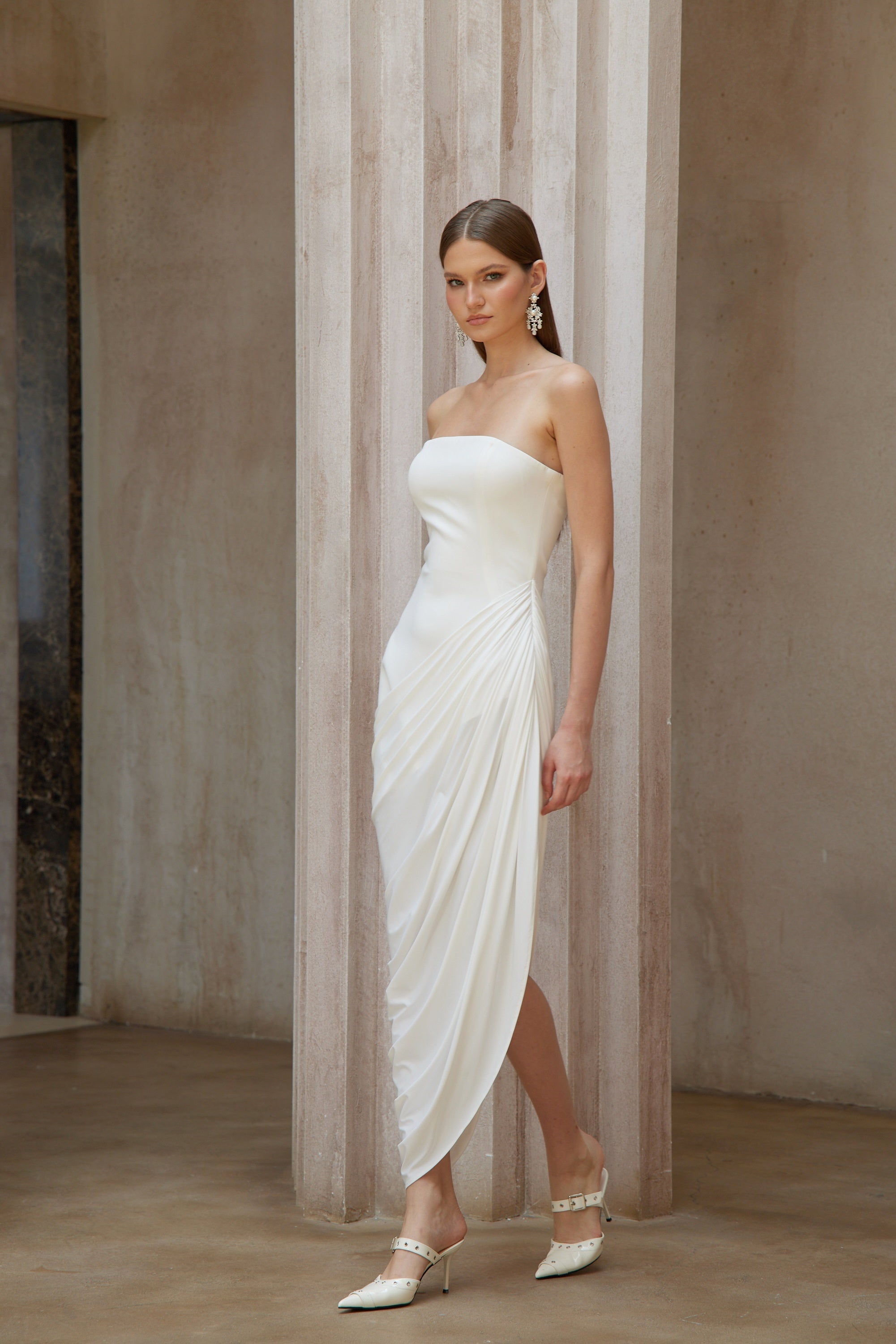White strapless maxi dress with a fitted bodice and a draped asymmetrical wrap skirt
