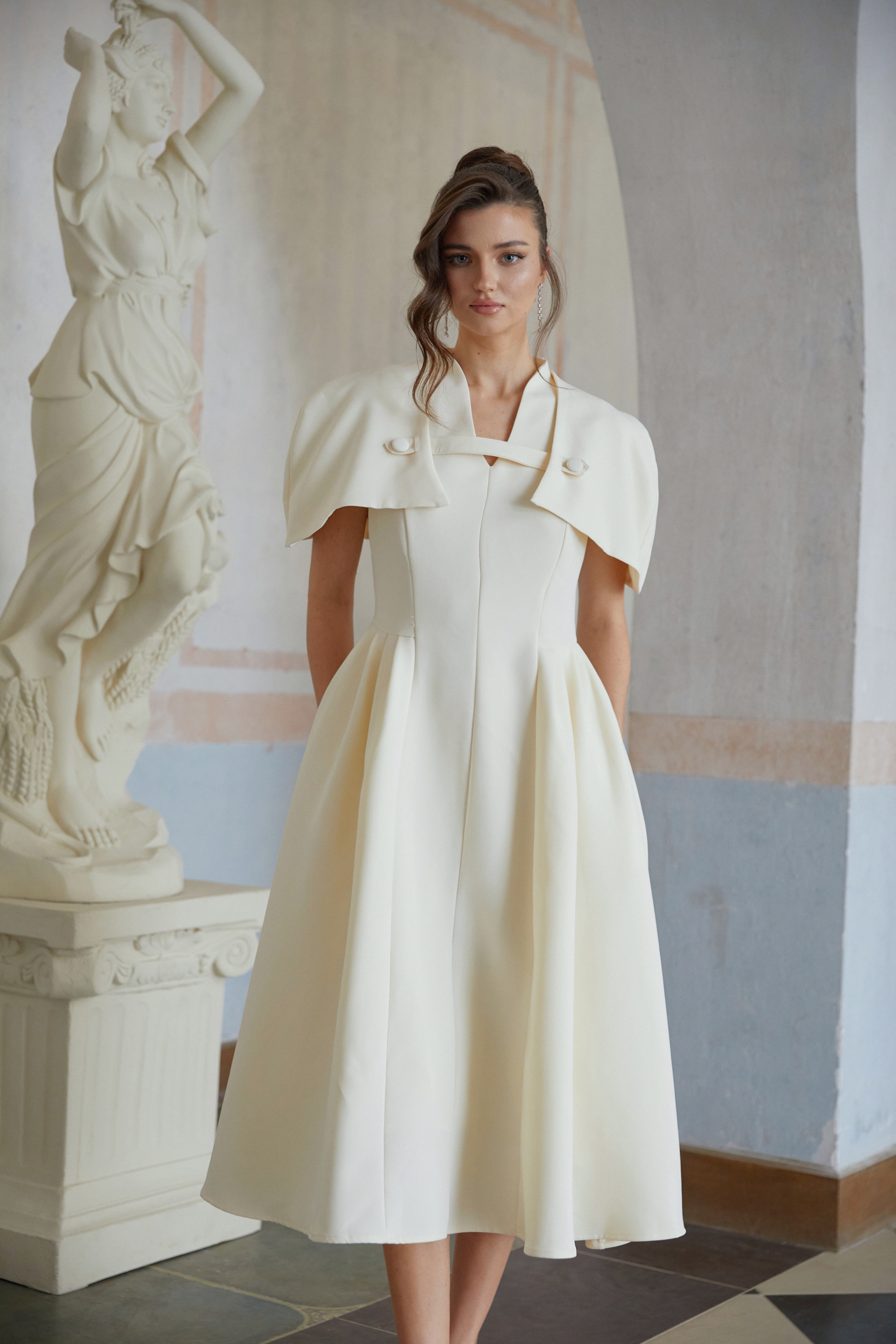 Cream midi dress with a structured capelet overlay and button details
