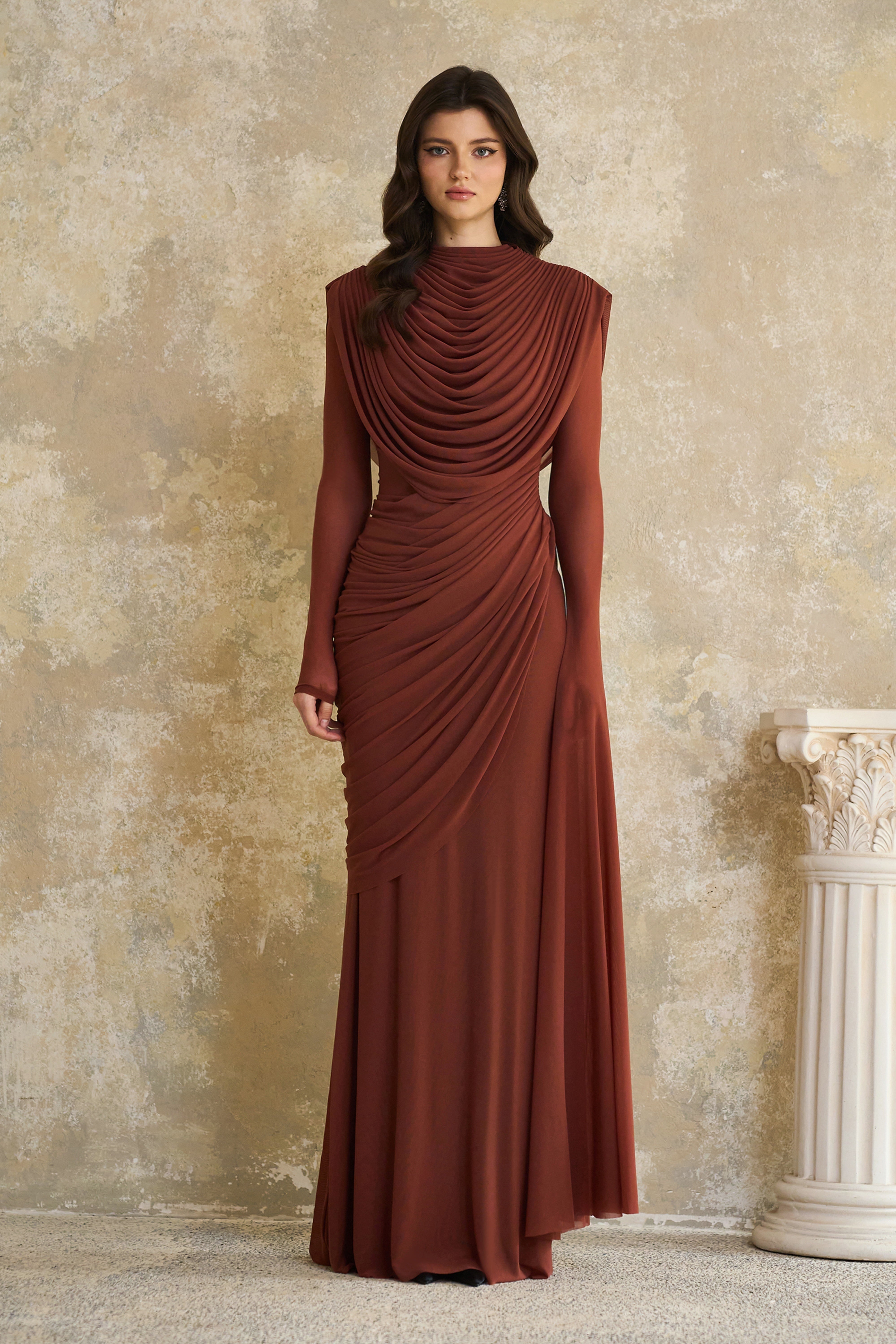Rust-colored long-sleeve maxi dress with a draped cowl neckline and pleated bodice