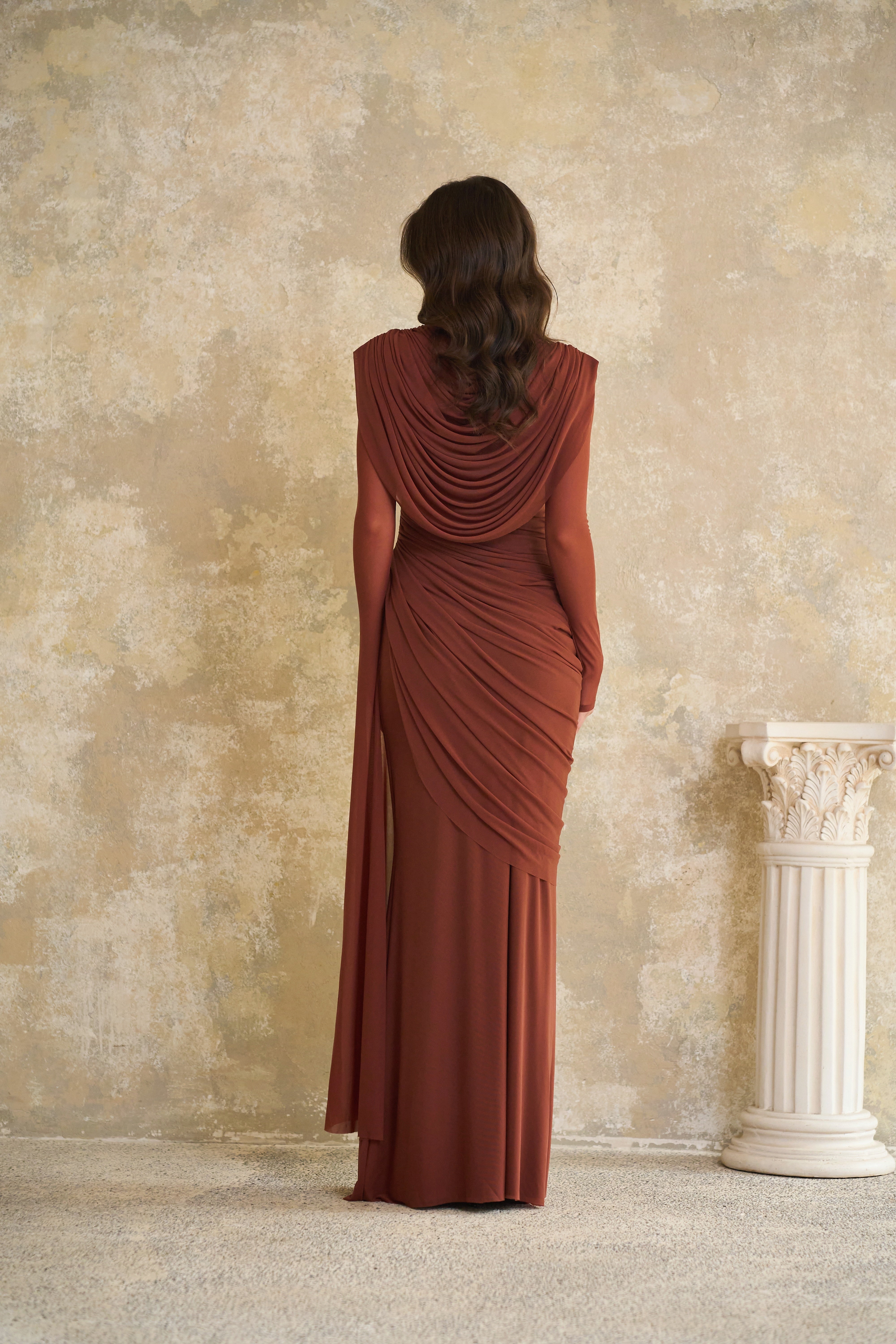 Rust-colored long-sleeve maxi dress with a draped cowl neckline and pleated bodice