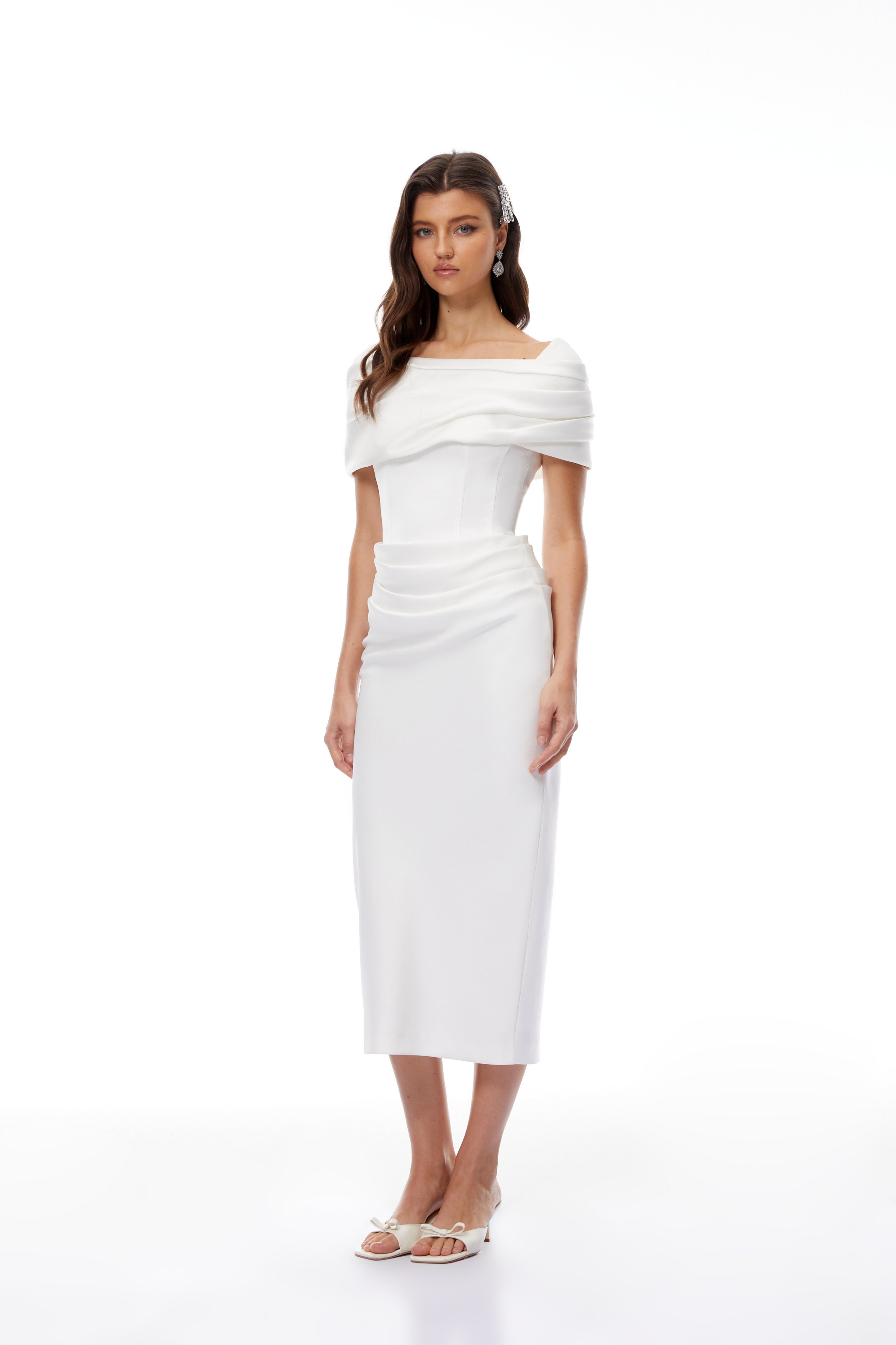 White off-the-shoulder gown with a draped bodice and cascading side ruffles