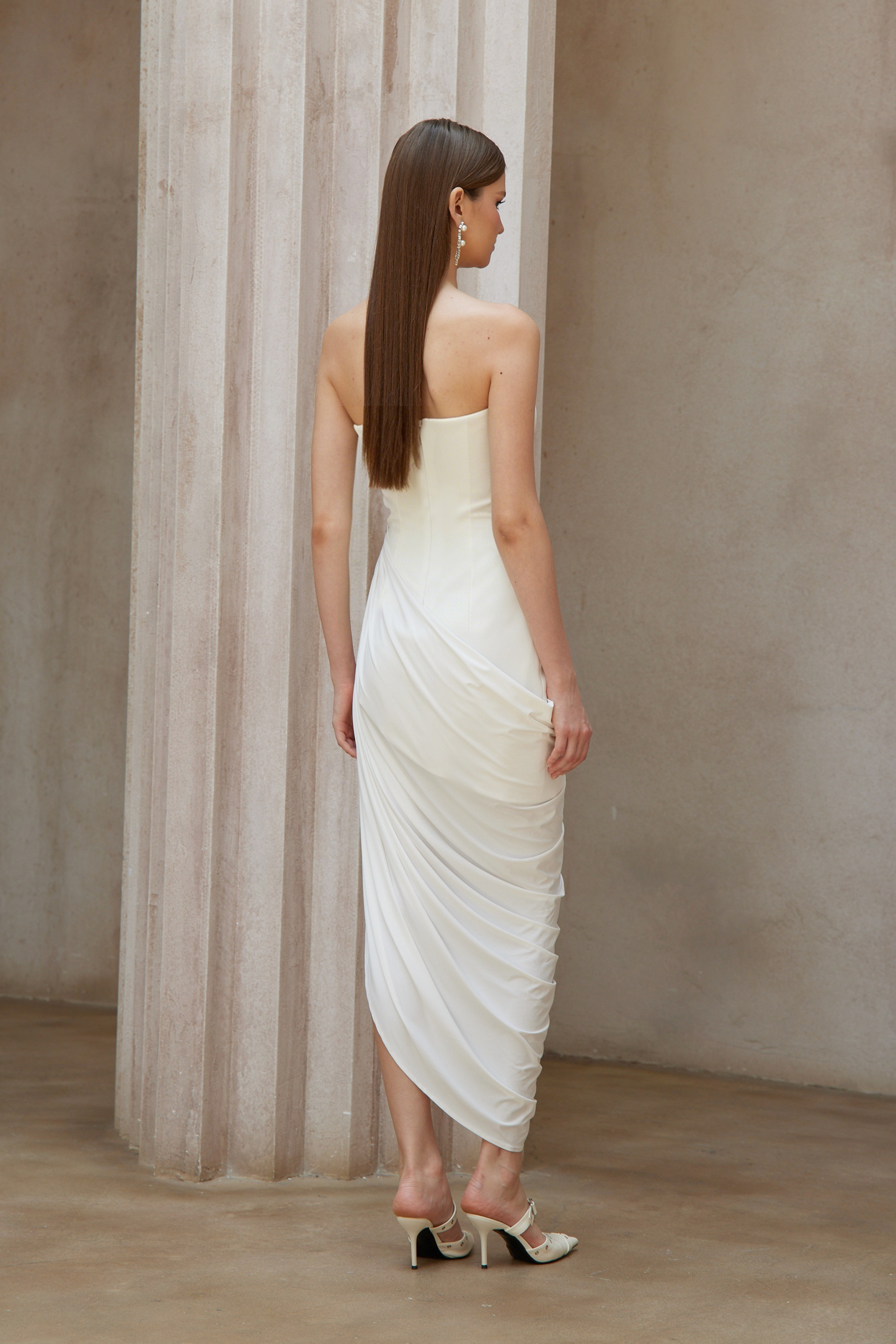 White strapless maxi dress with a fitted bodice and a draped asymmetrical wrap skirt