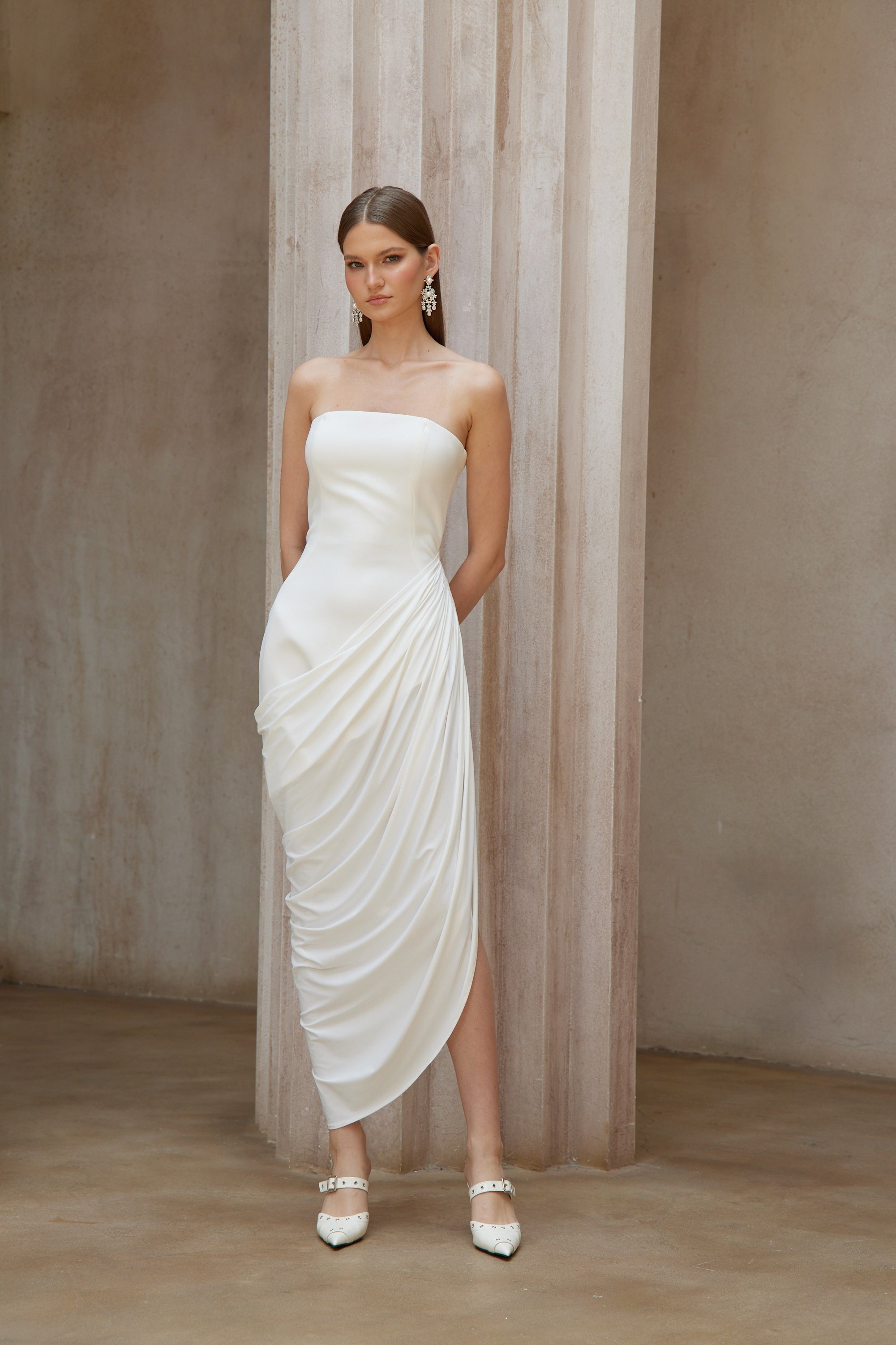 White strapless maxi dress with a fitted bodice and a draped asymmetrical wrap skirt