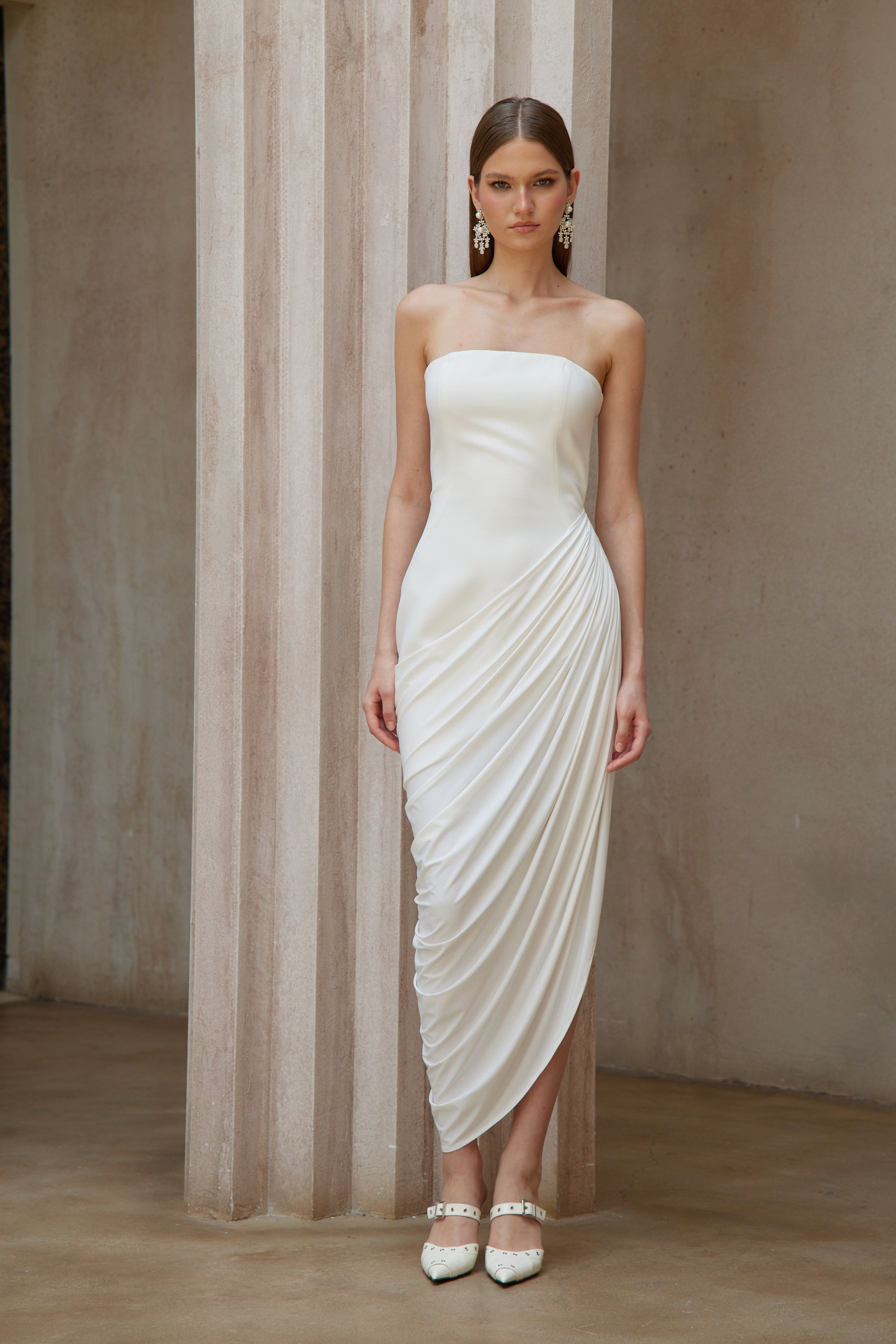 White strapless maxi dress with a fitted bodice and a draped asymmetrical wrap skirt