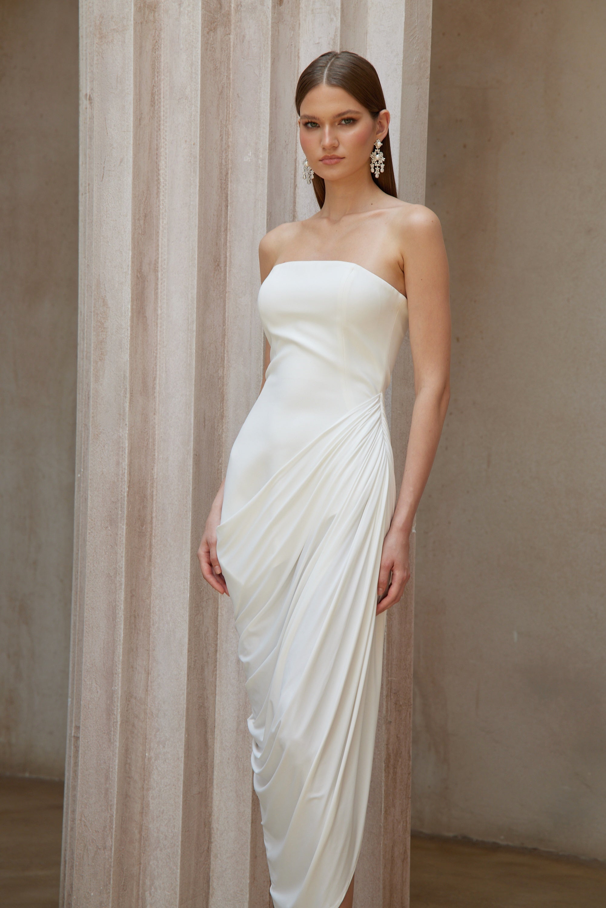 White strapless maxi dress with a fitted bodice and a draped asymmetrical wrap skirt