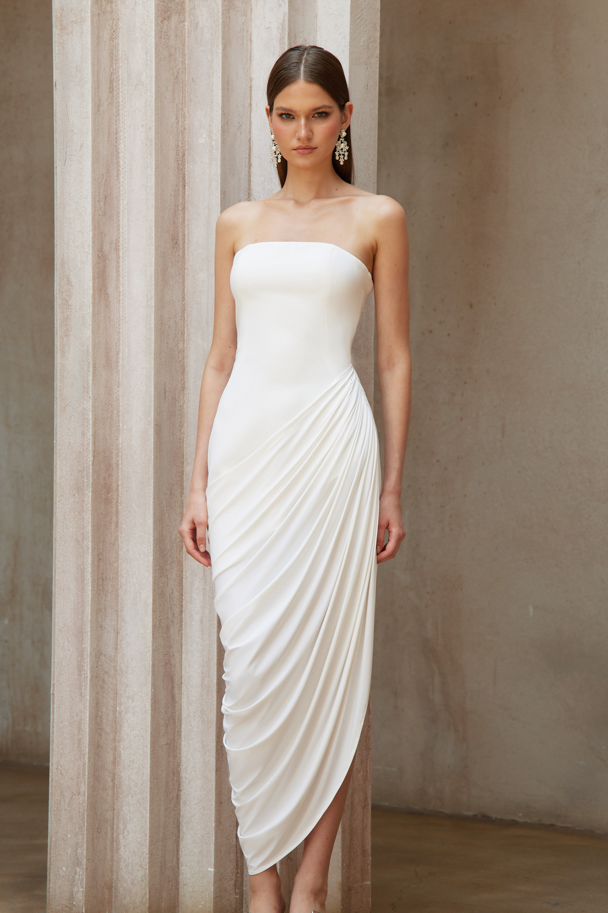 White strapless maxi dress with a fitted bodice and a draped asymmetrical wrap skirt