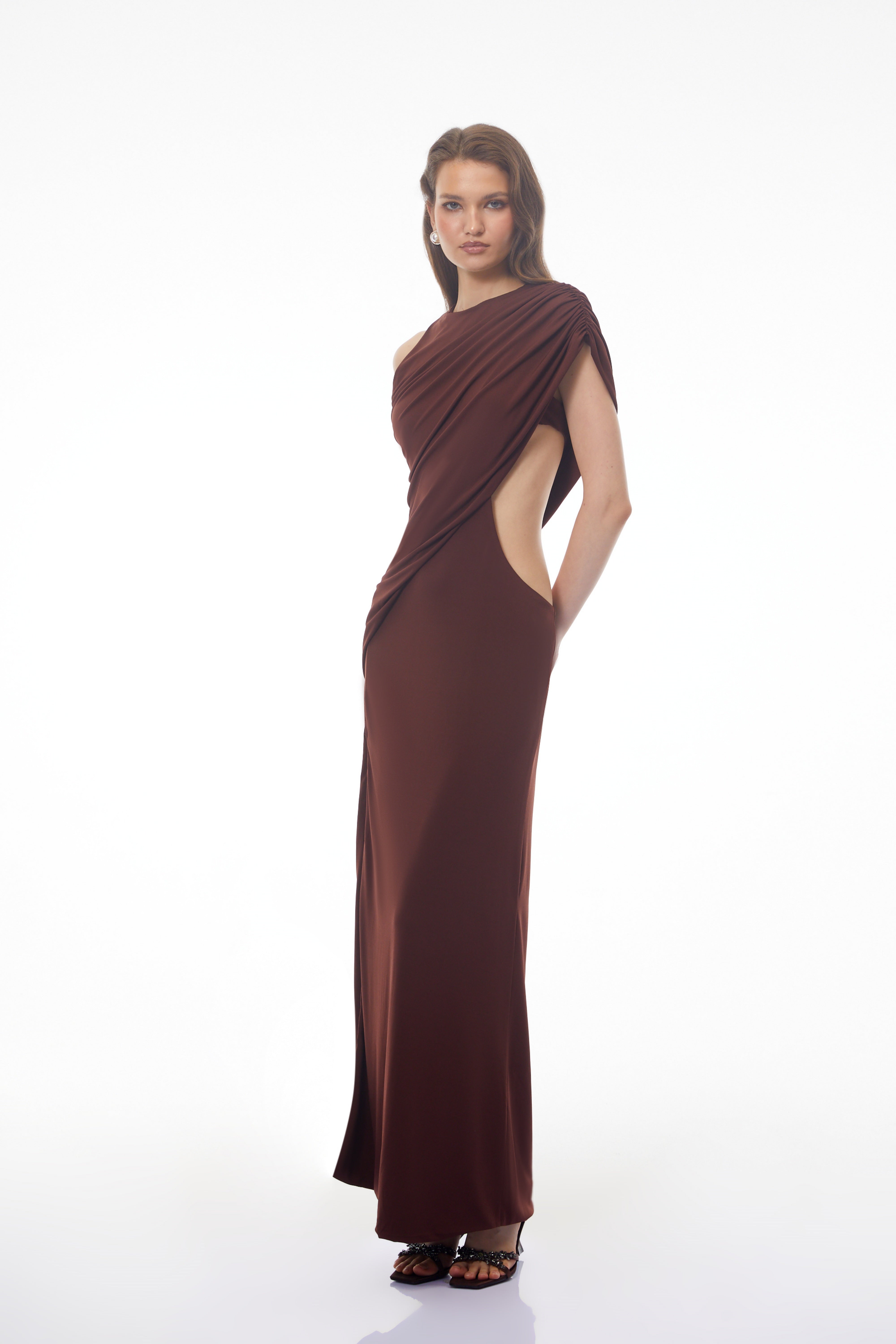 Dark brown maxi dress featuring a one-shoulder neckline, asymmetric draped overlay, and a high front slit