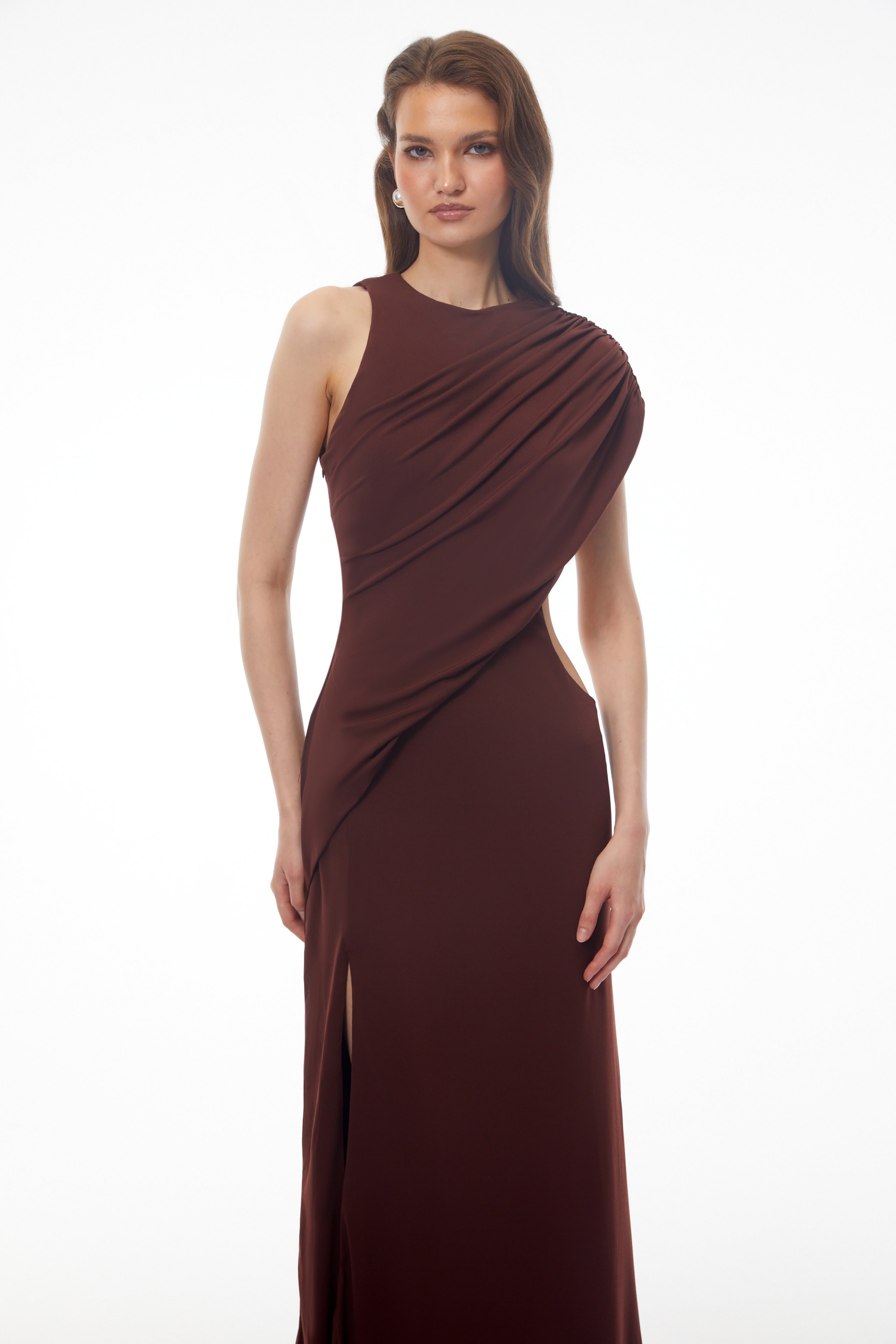 Dark brown maxi dress featuring a one-shoulder neckline, asymmetric draped overlay, and a high front slit