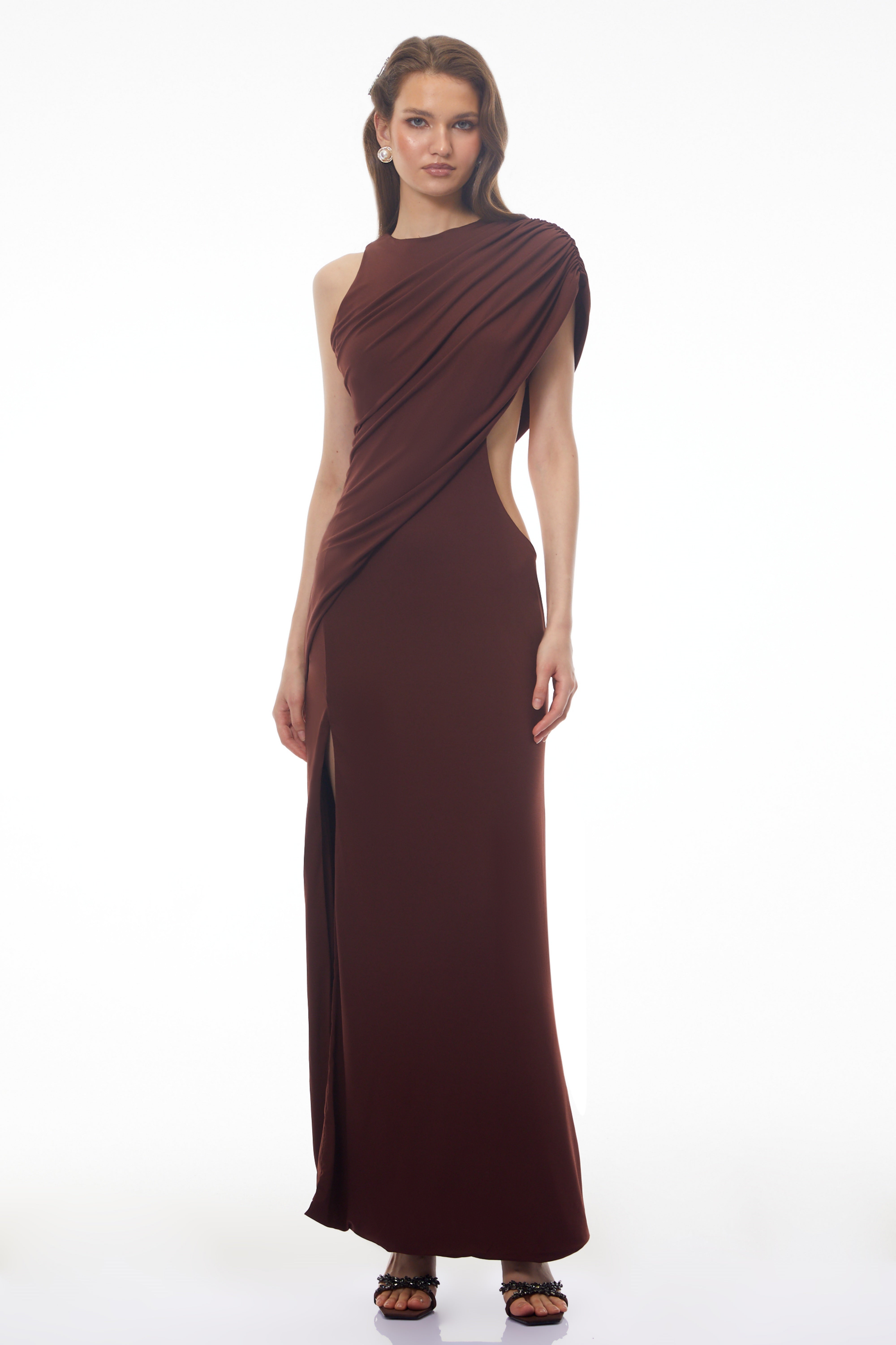 Dark brown maxi dress featuring a one-shoulder neckline, asymmetric draped overlay, and a high front slit