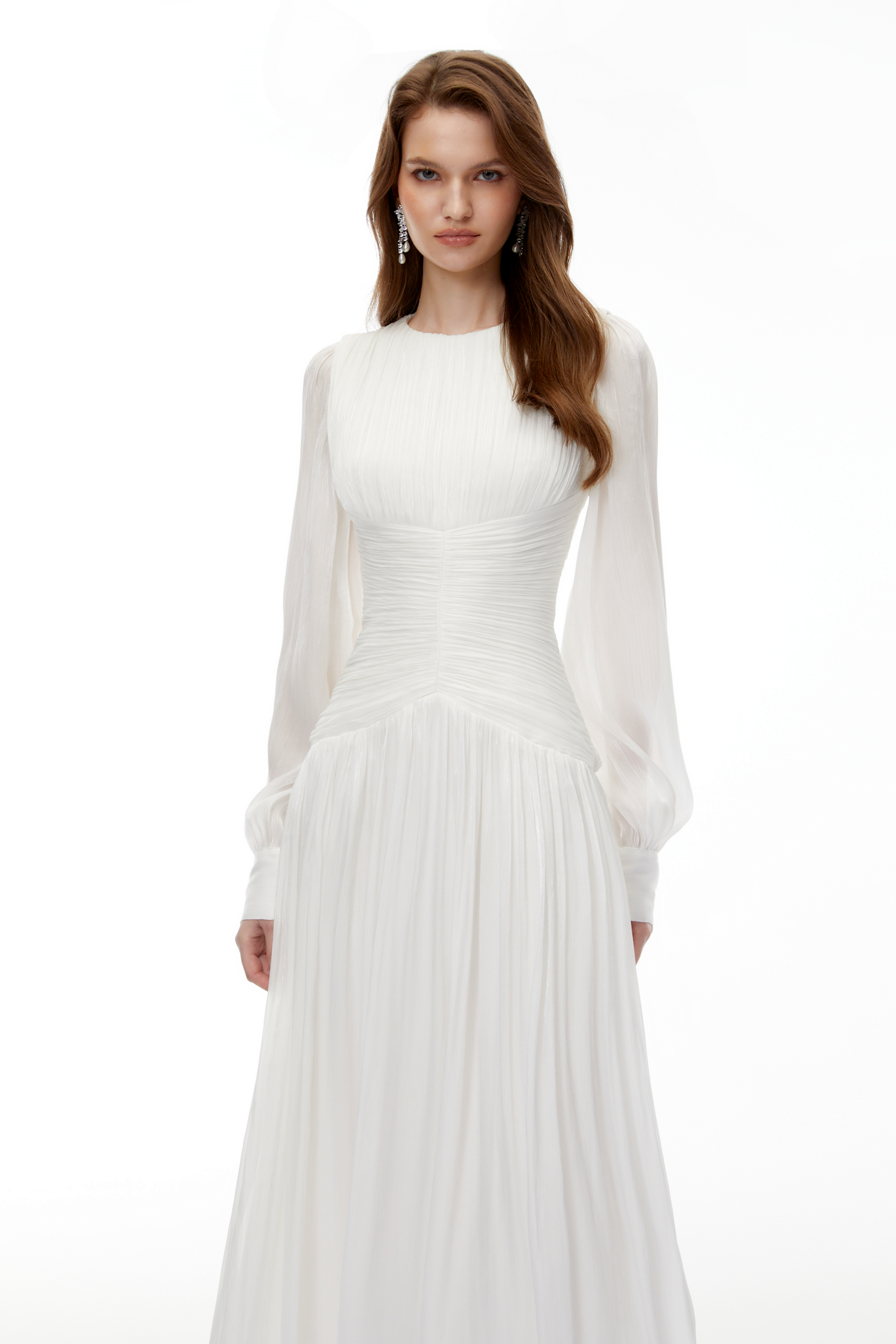 White maxi dress with a ruched bodice, round neckline, and long sheer sleeves