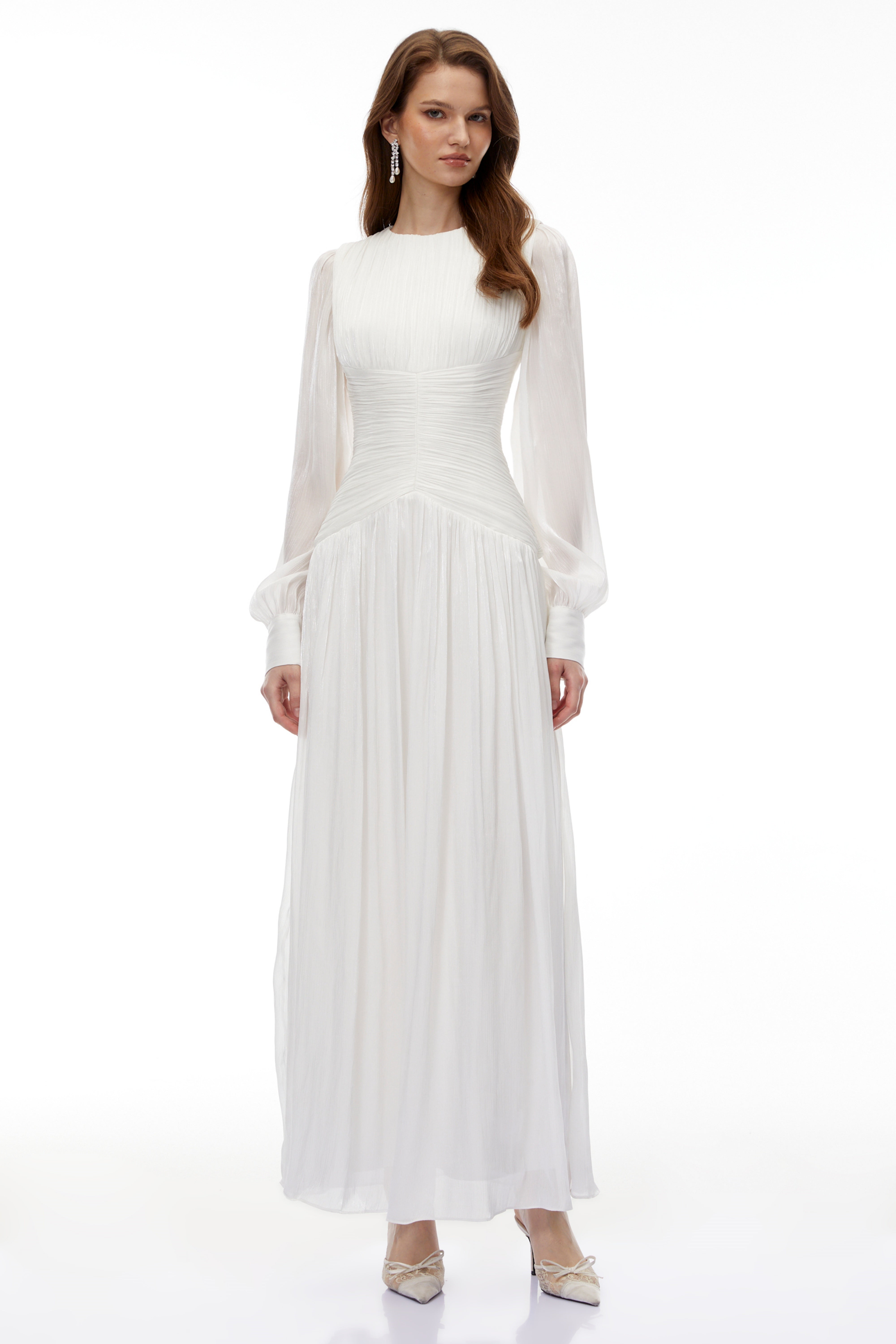 White maxi dress with a ruched bodice, round neckline, and long sheer sleeves