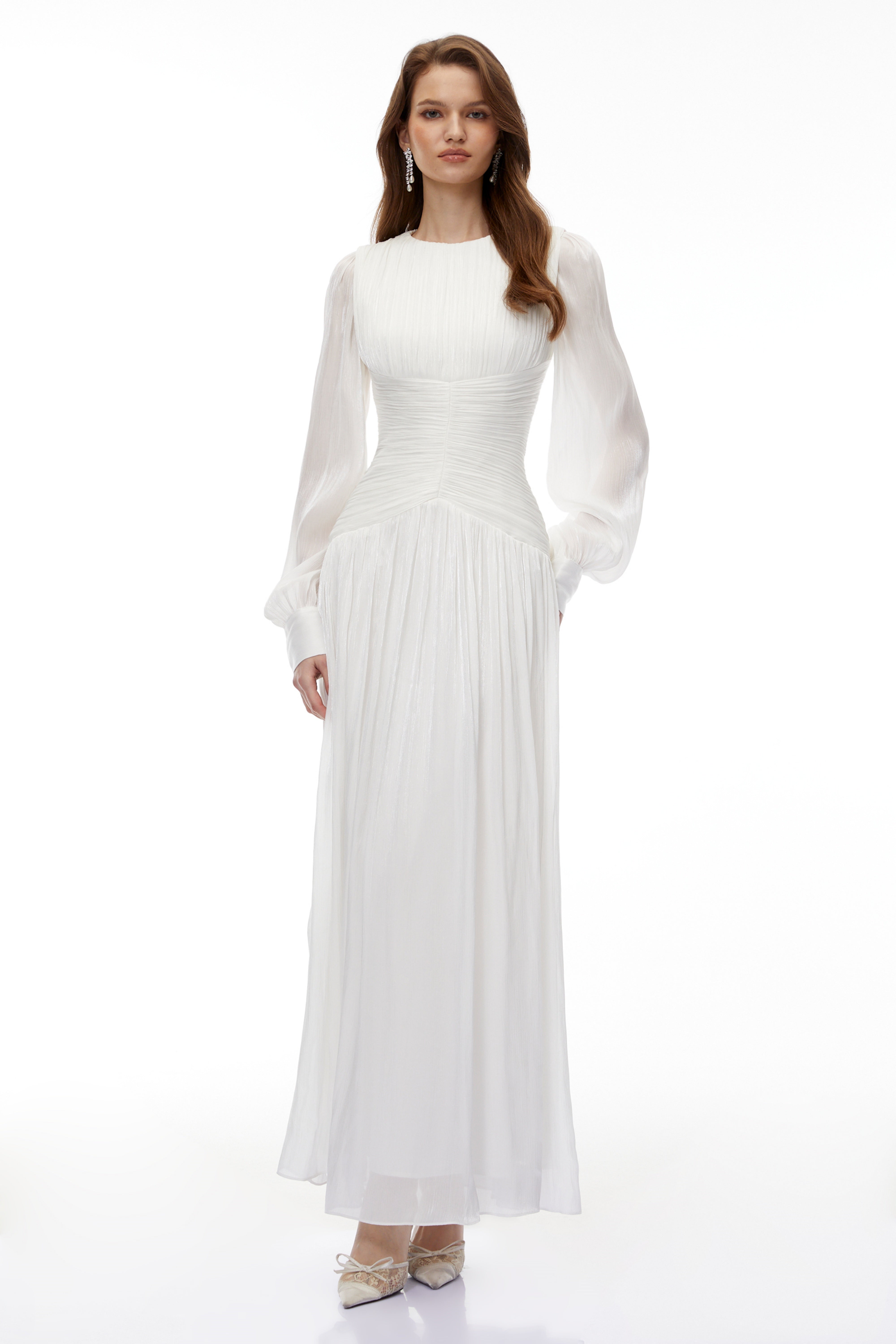 White maxi dress with a ruched bodice, round neckline, and long sheer sleeves