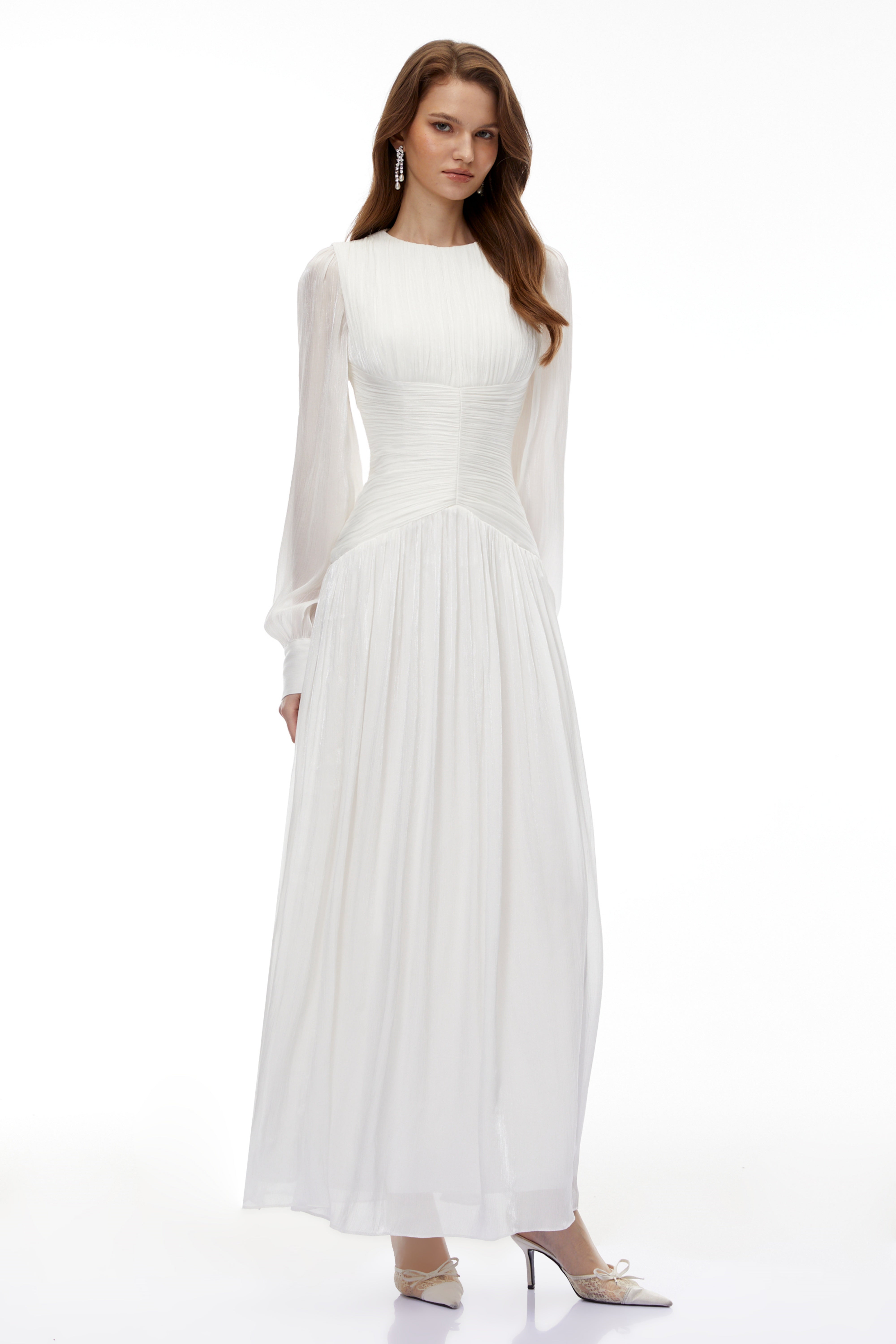 White maxi dress with a ruched bodice, round neckline, and long sheer sleeves