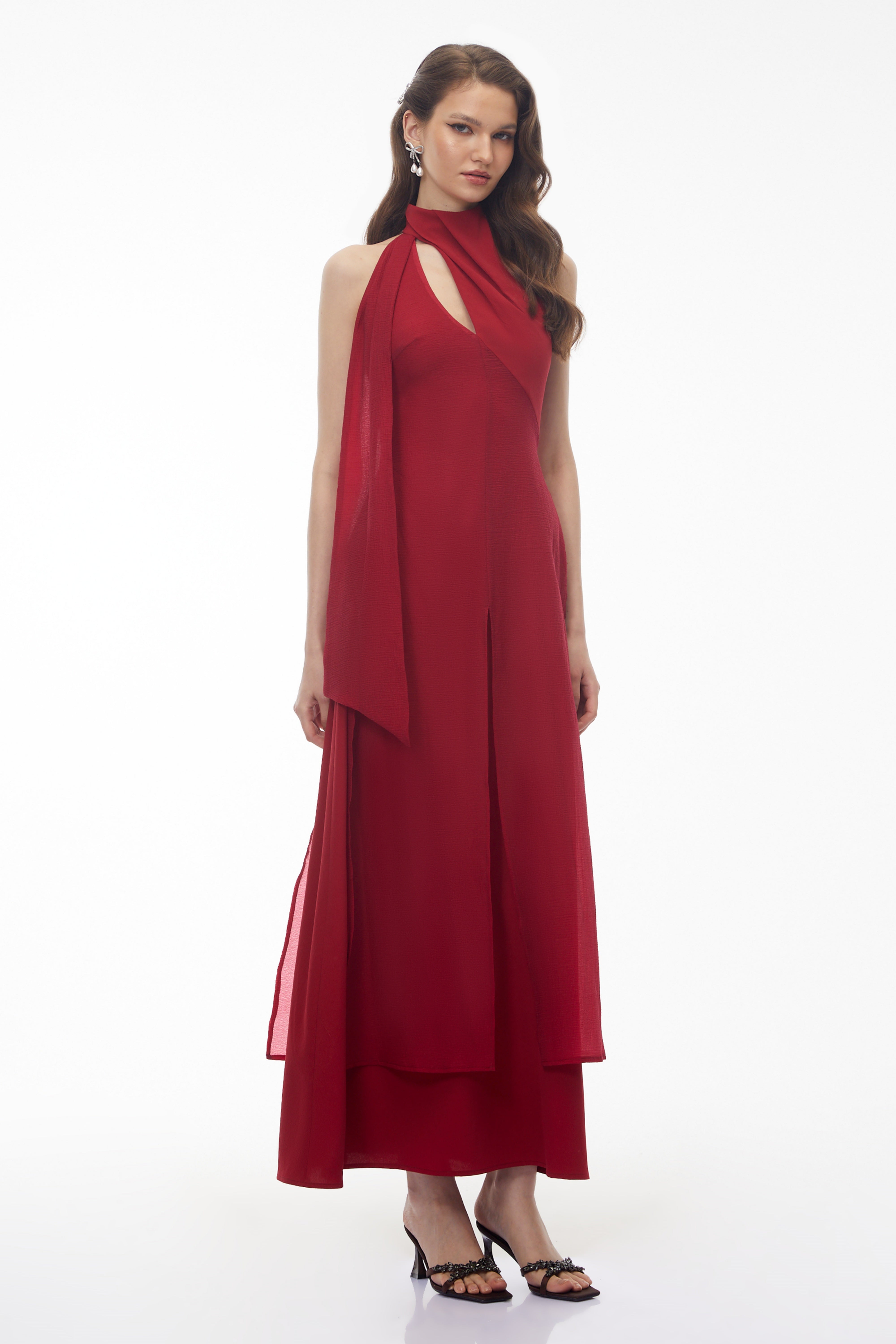 Red maxi dress with a high halter neckline, an asymmetrical cutout, and a long draped scarf detail
