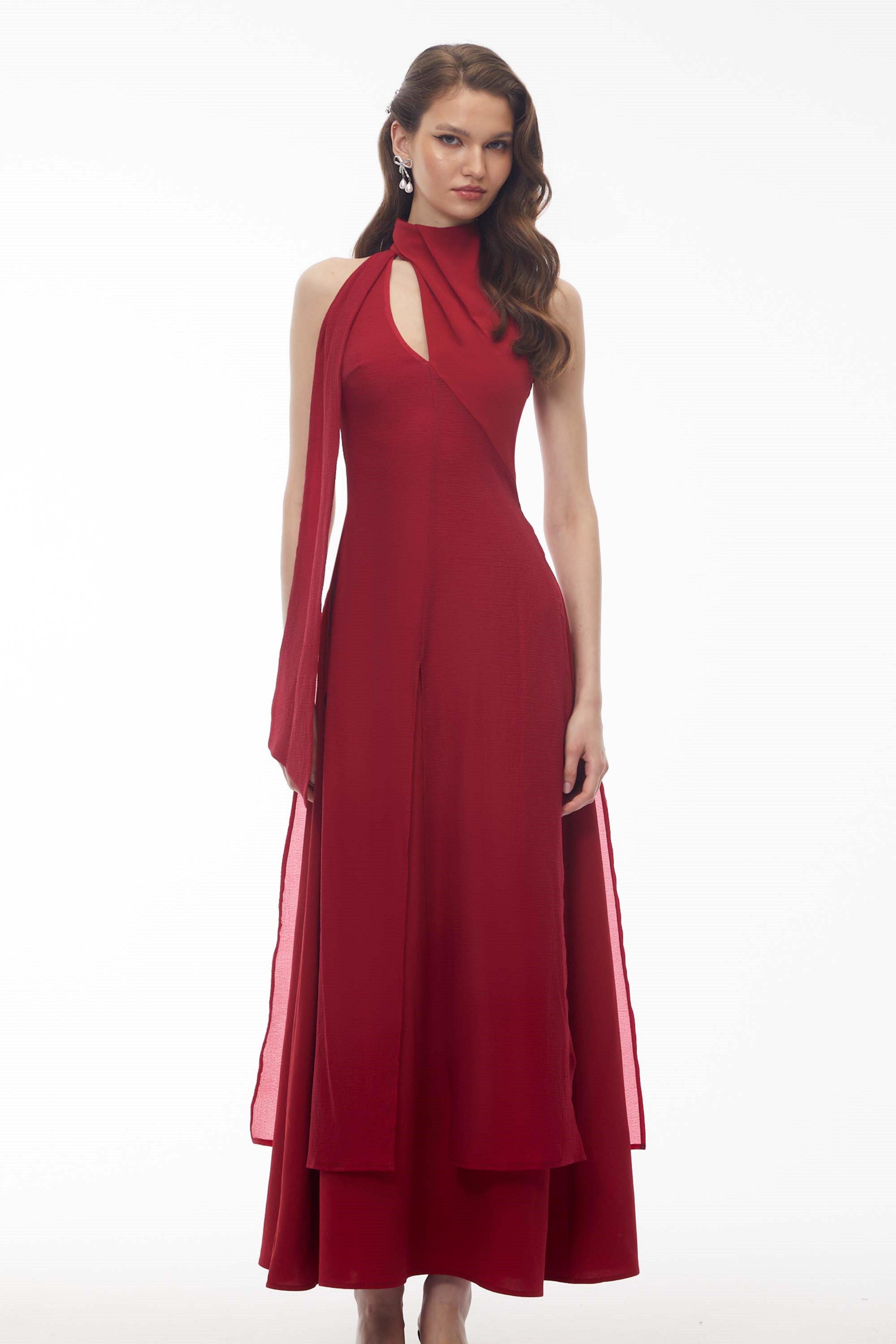 Red maxi dress with a high halter neckline, an asymmetrical cutout, and a long draped scarf detail