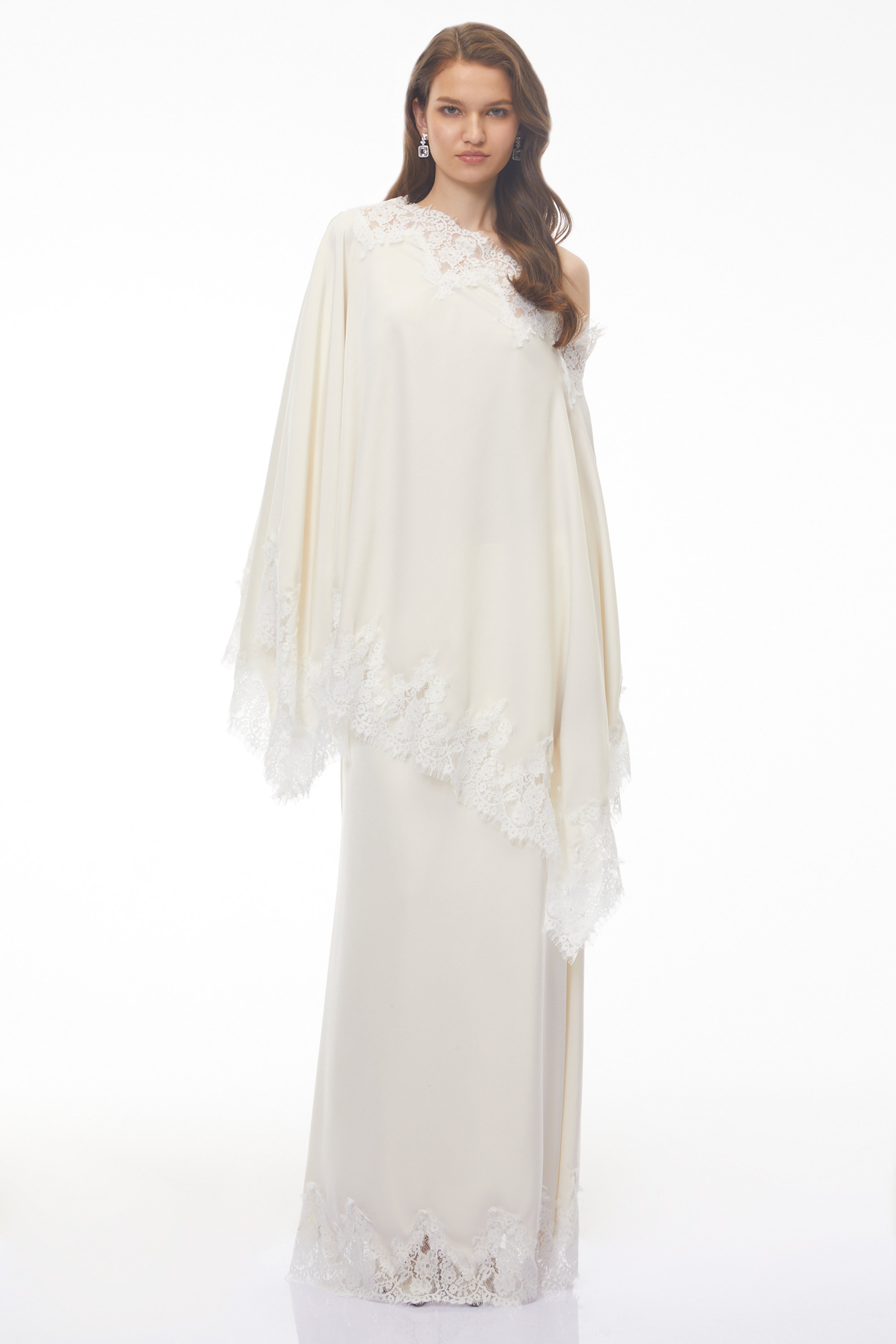 Off-white silk maxi dress with white lace trim, featuring a matching asymmetrical lace-edged poncho cape