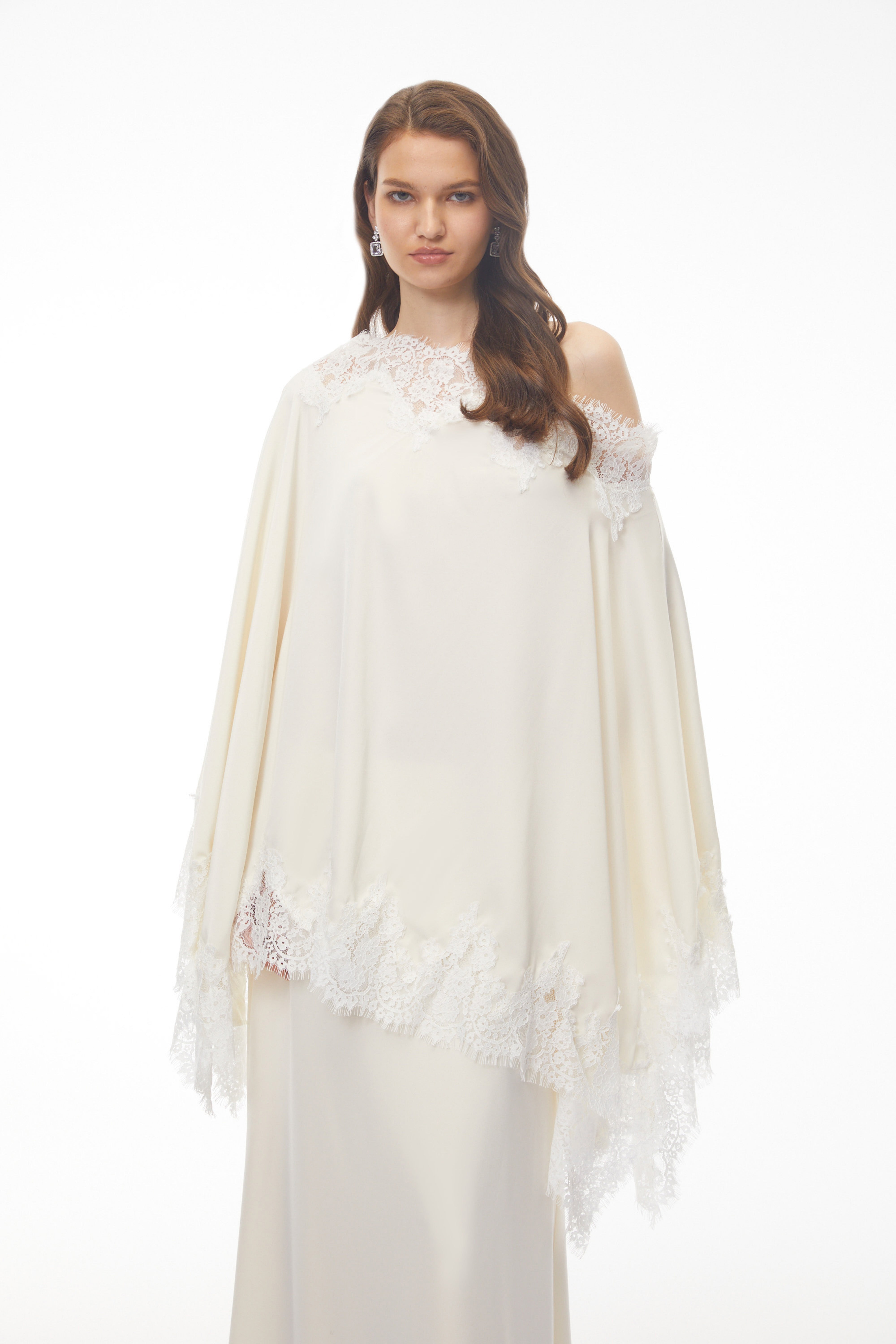 Off-white silk maxi dress with white lace trim, featuring a matching asymmetrical lace-edged poncho cape
