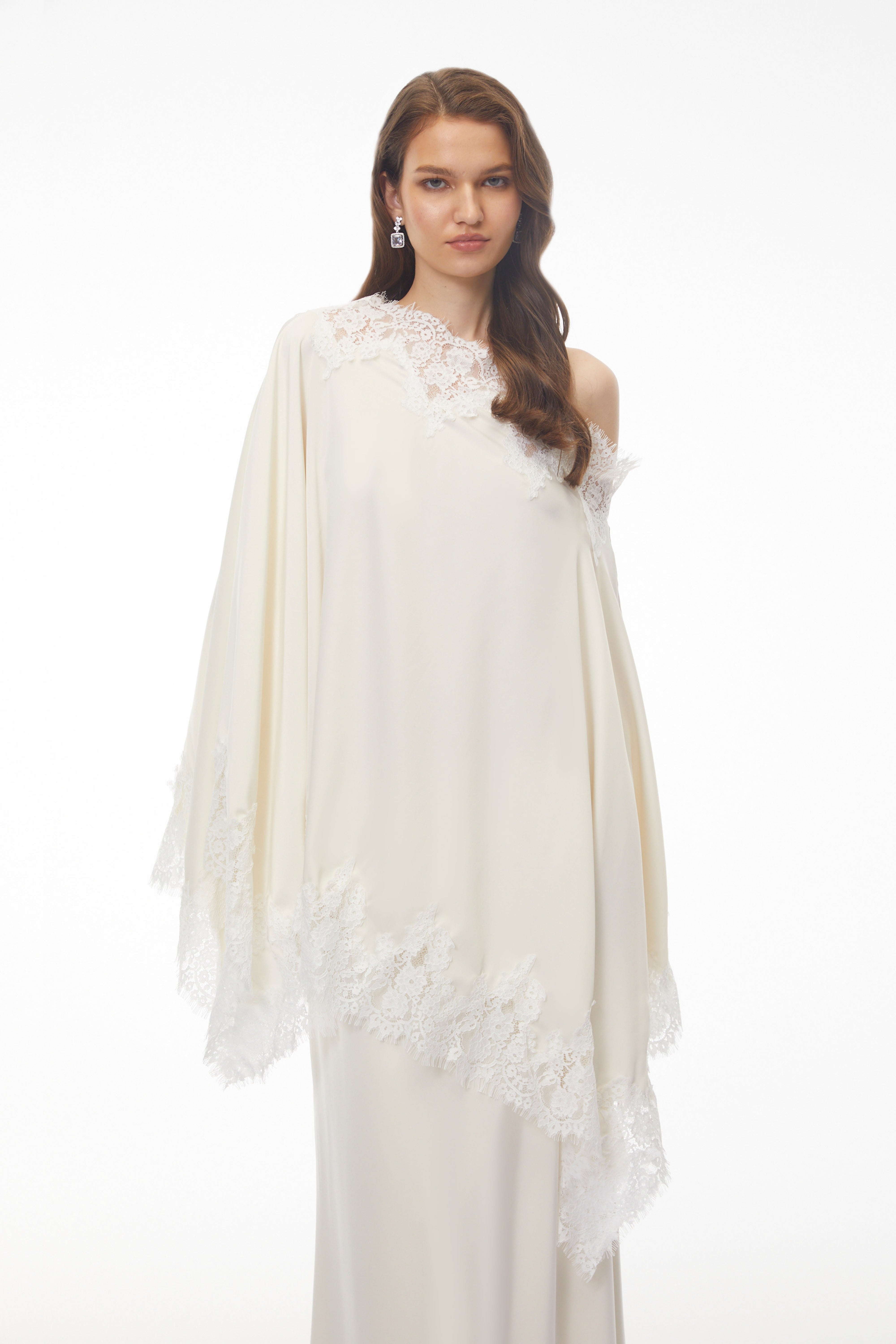 Off-white silk maxi dress with white lace trim, featuring a matching asymmetrical lace-edged poncho cape
