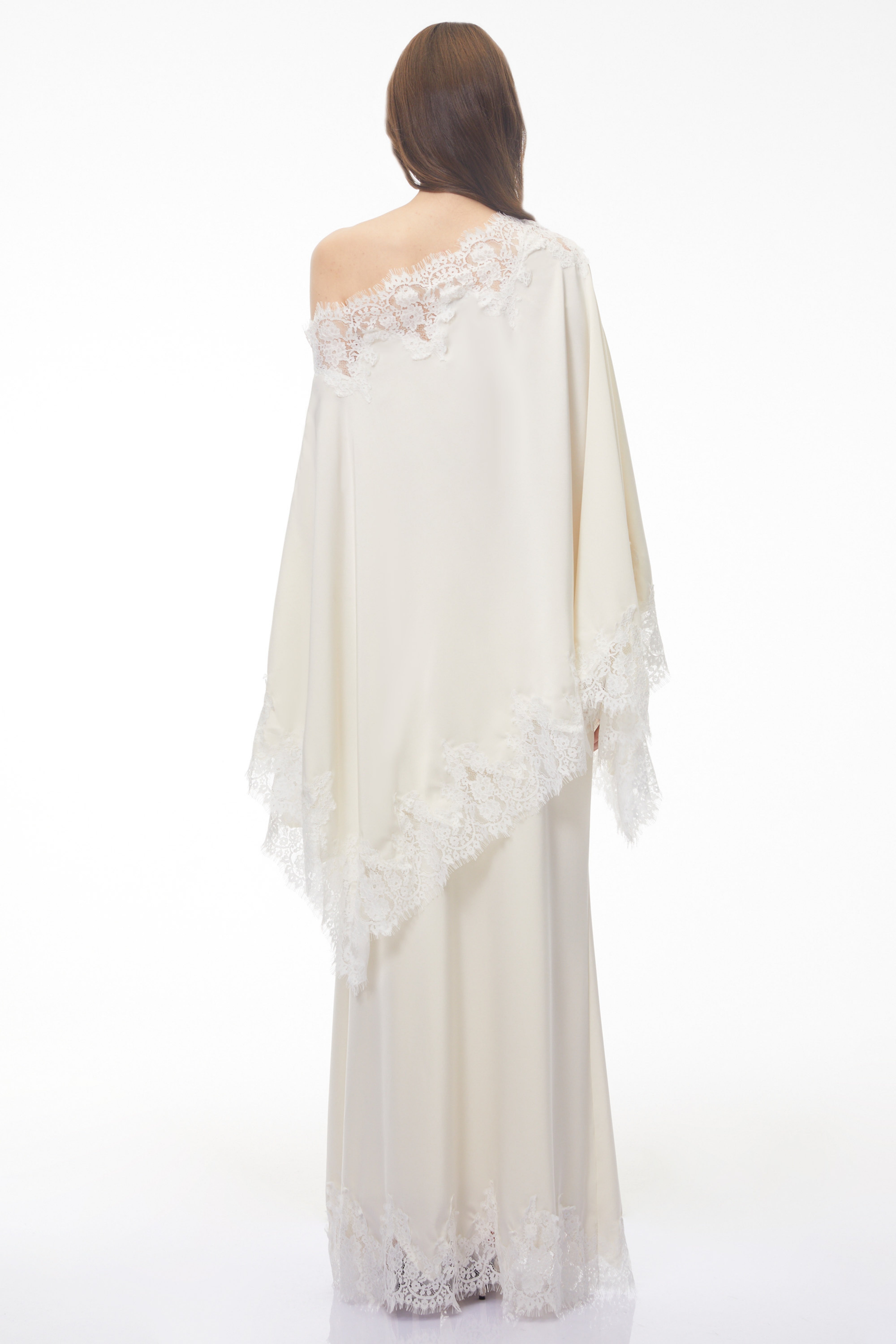 Off-white silk maxi dress with white lace trim, featuring a matching asymmetrical lace-edged poncho cape