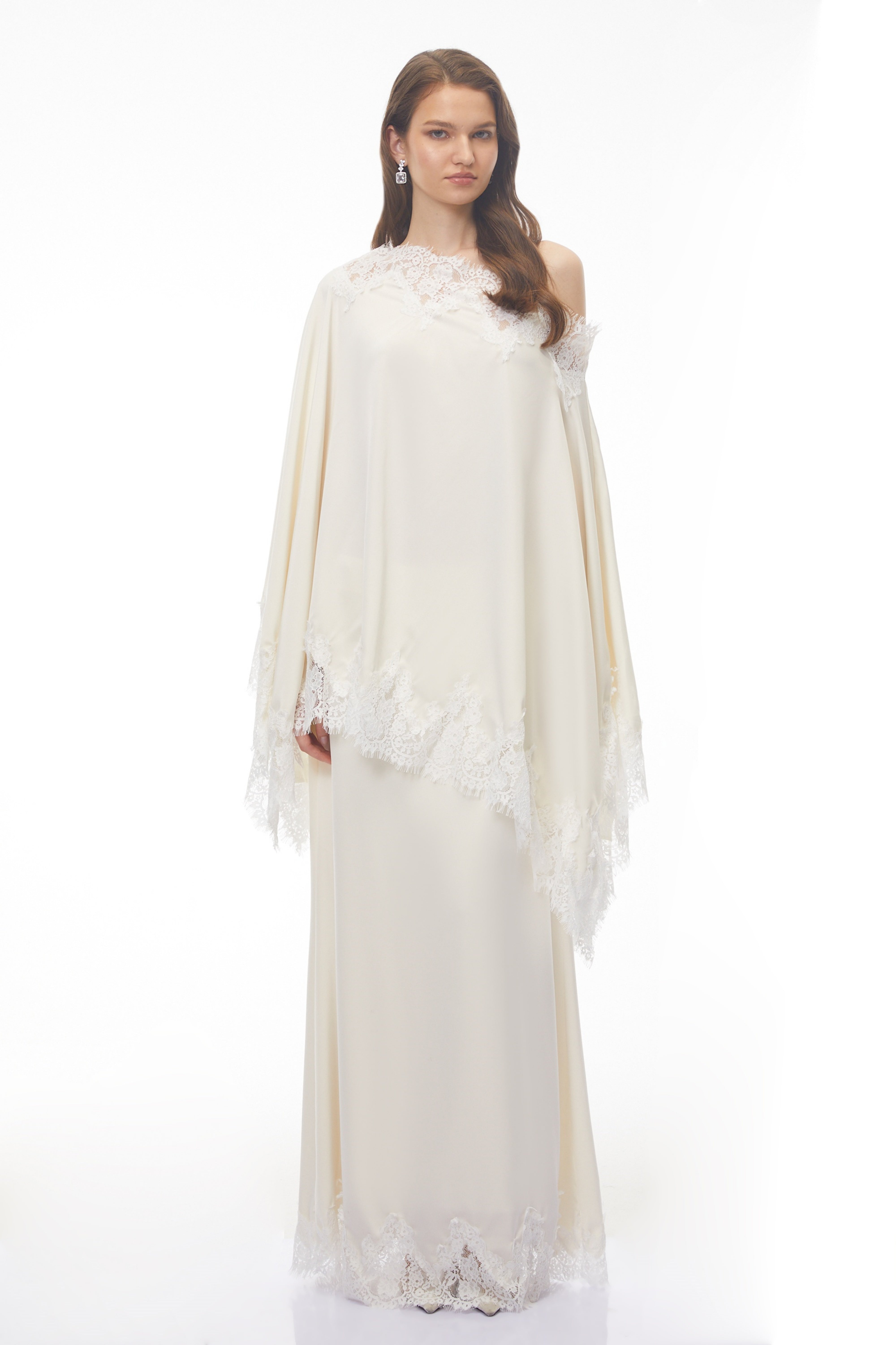 Off-white silk maxi dress with white lace trim, featuring a matching asymmetrical lace-edged poncho cape