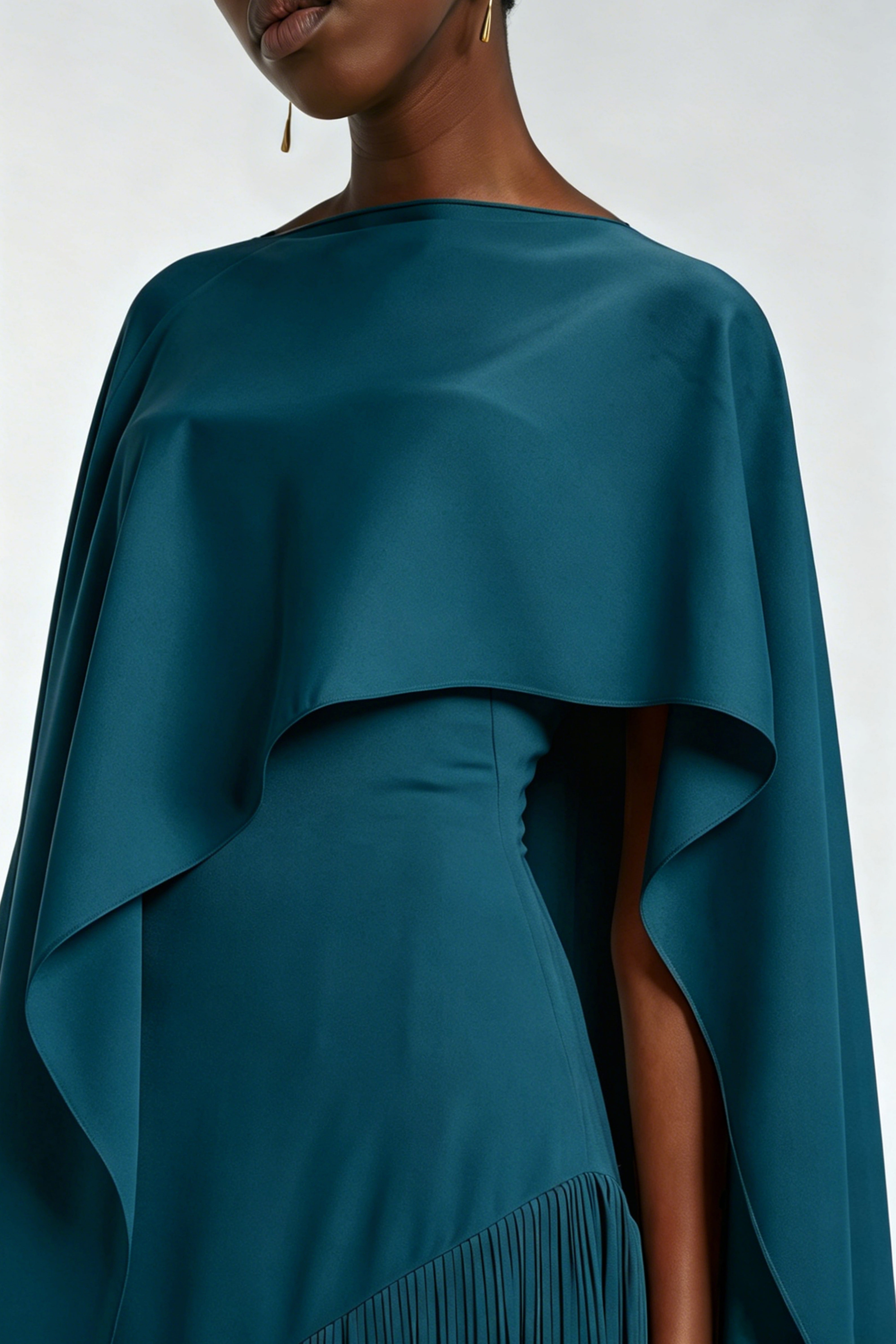 Teal blue maxi dress with a matching overlay cape and a long asymmetric fringe skirt