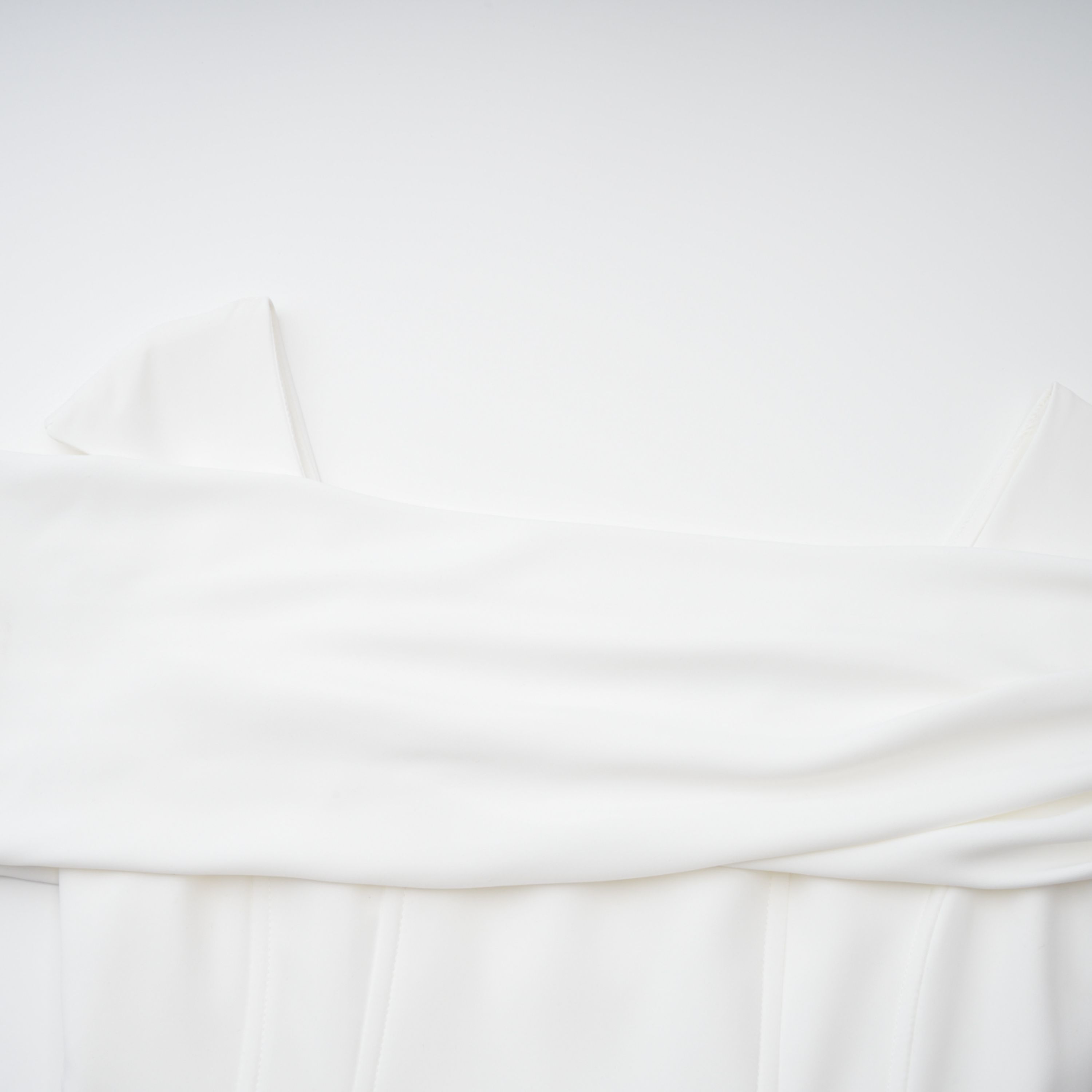 White off-the-shoulder gown with a draped bodice and cascading side ruffles