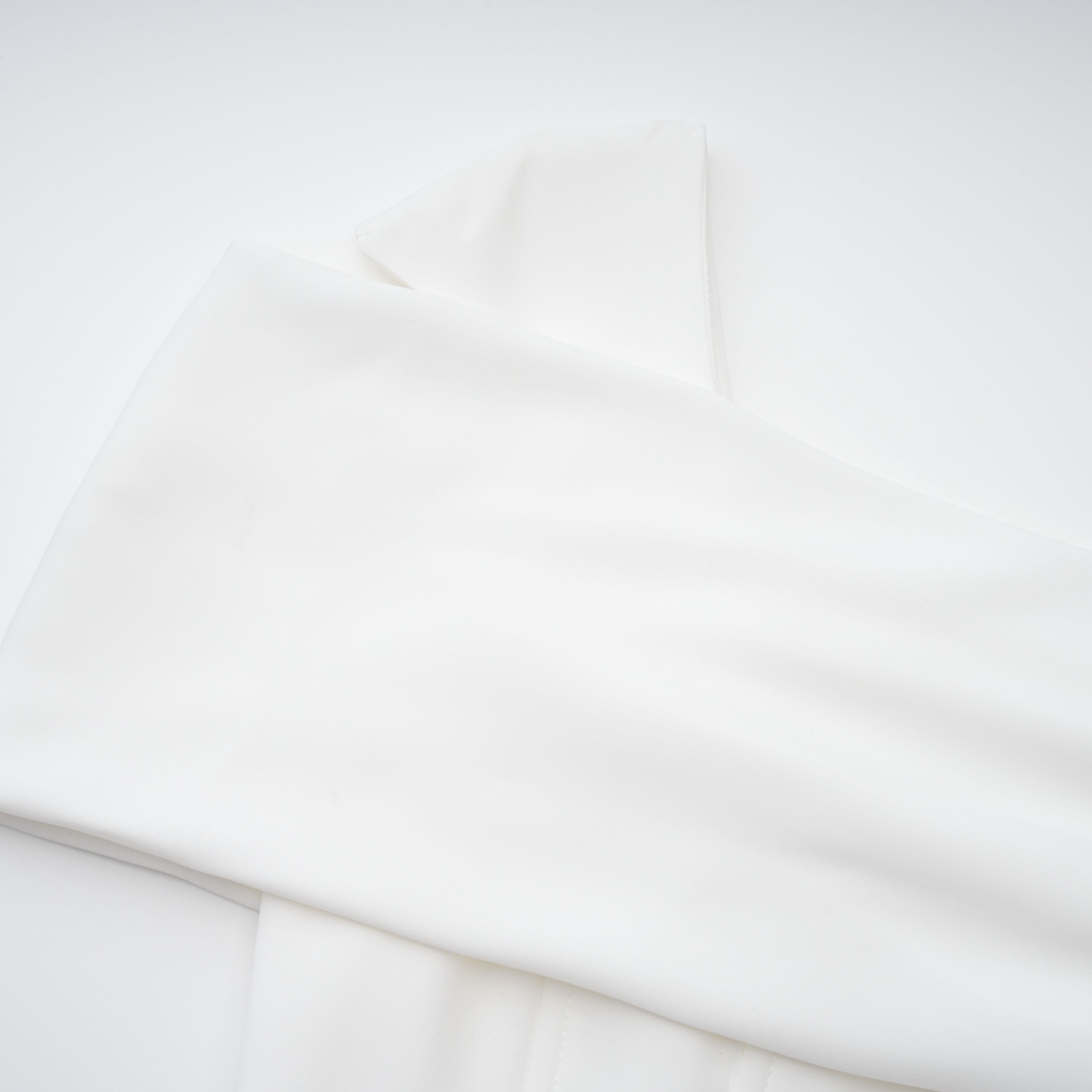 White off-the-shoulder gown with a draped bodice and cascading side ruffles