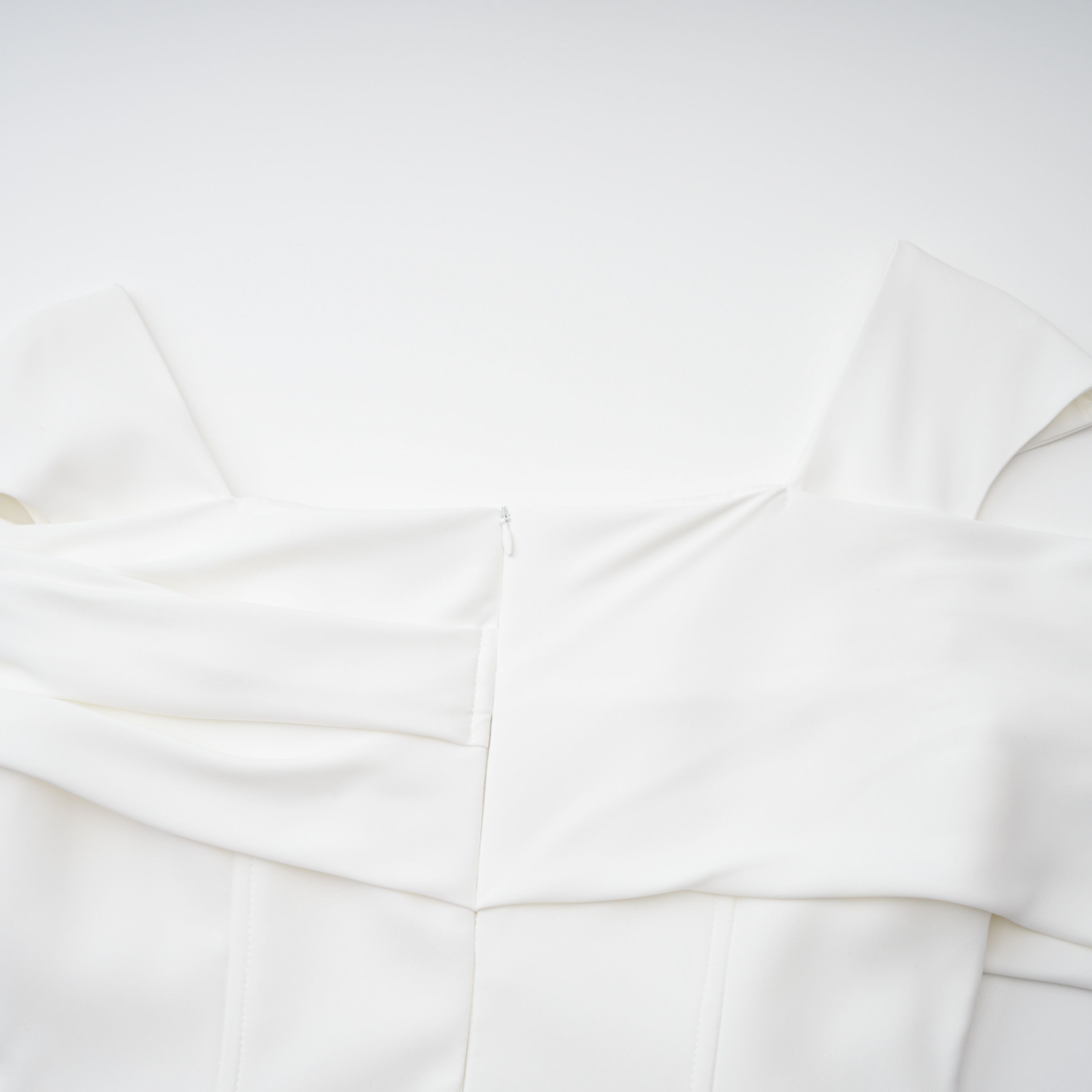 White off-the-shoulder gown with a draped bodice and cascading side ruffles