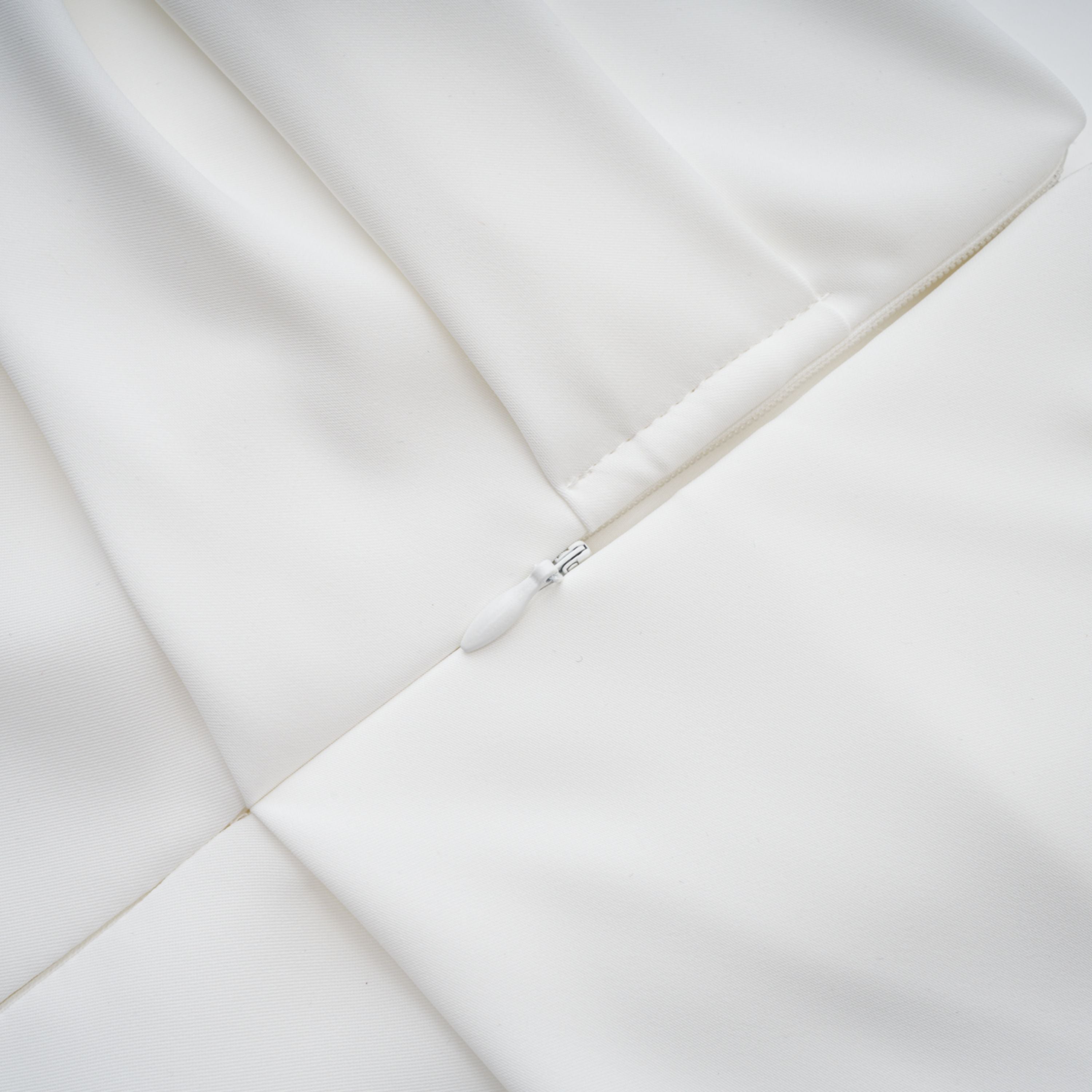 White off-the-shoulder gown with a draped bodice and cascading side ruffles