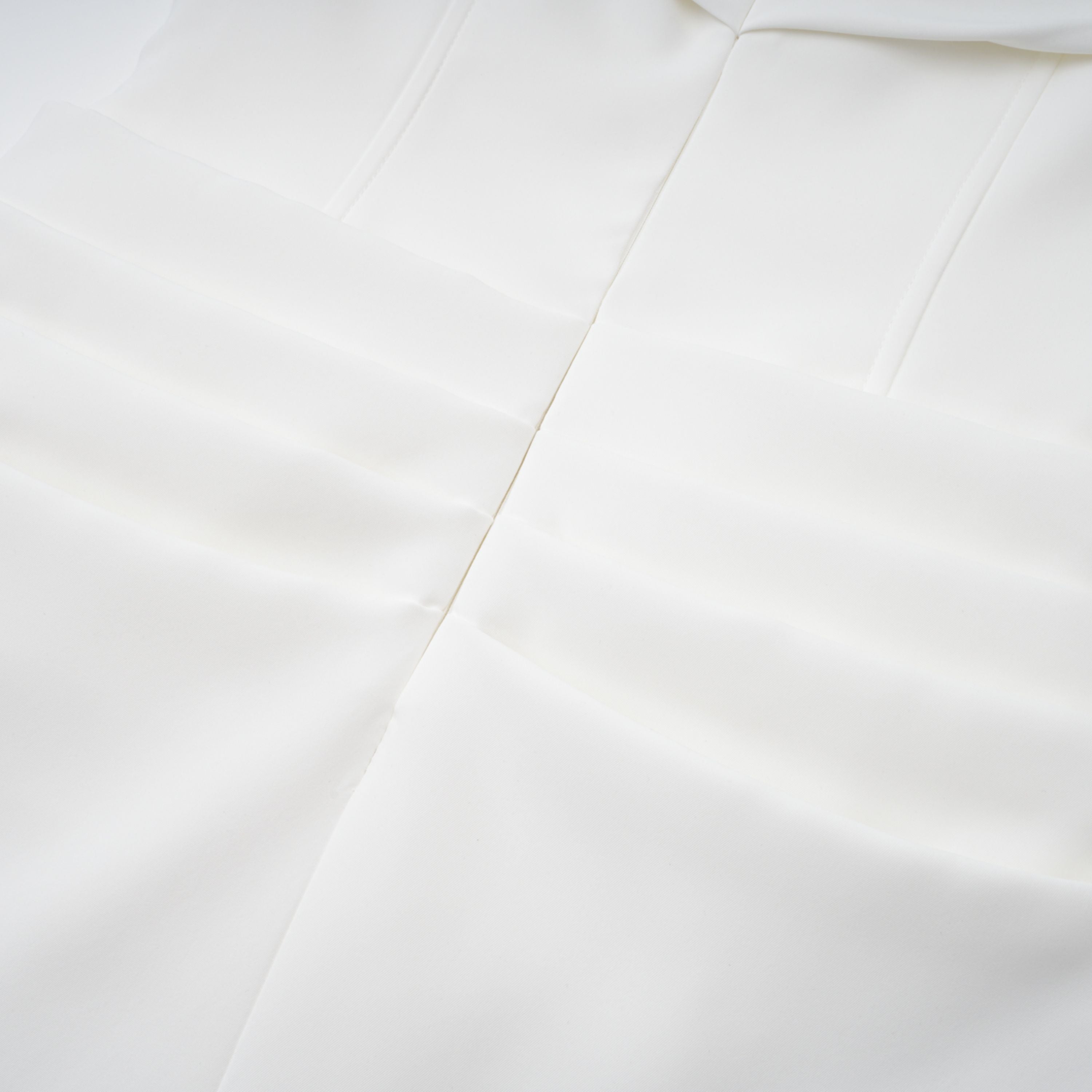 White off-the-shoulder gown with a draped bodice and cascading side ruffles