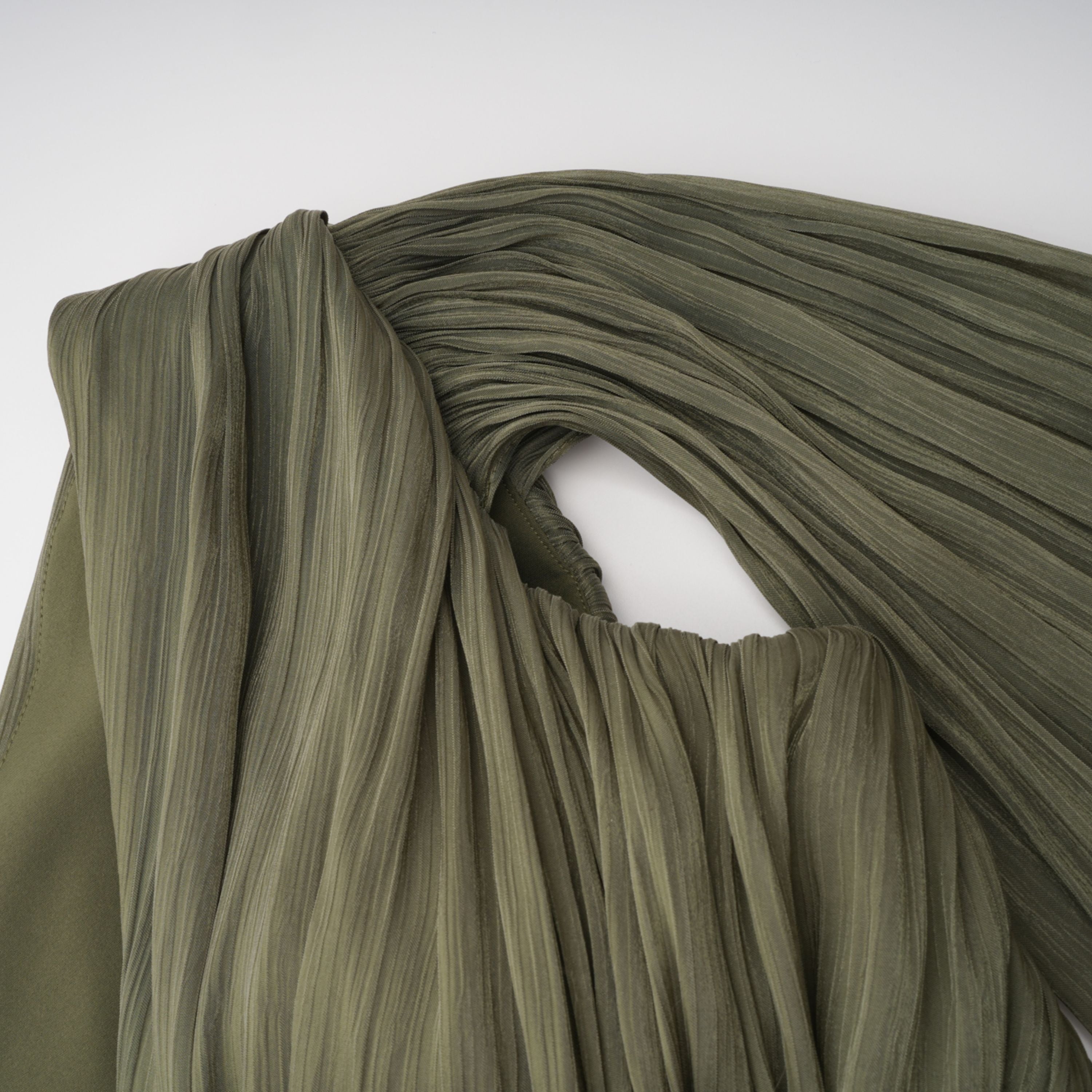 Olive green pleated one-shoulder gown with beaded embellishments and a long draped shoulder cape