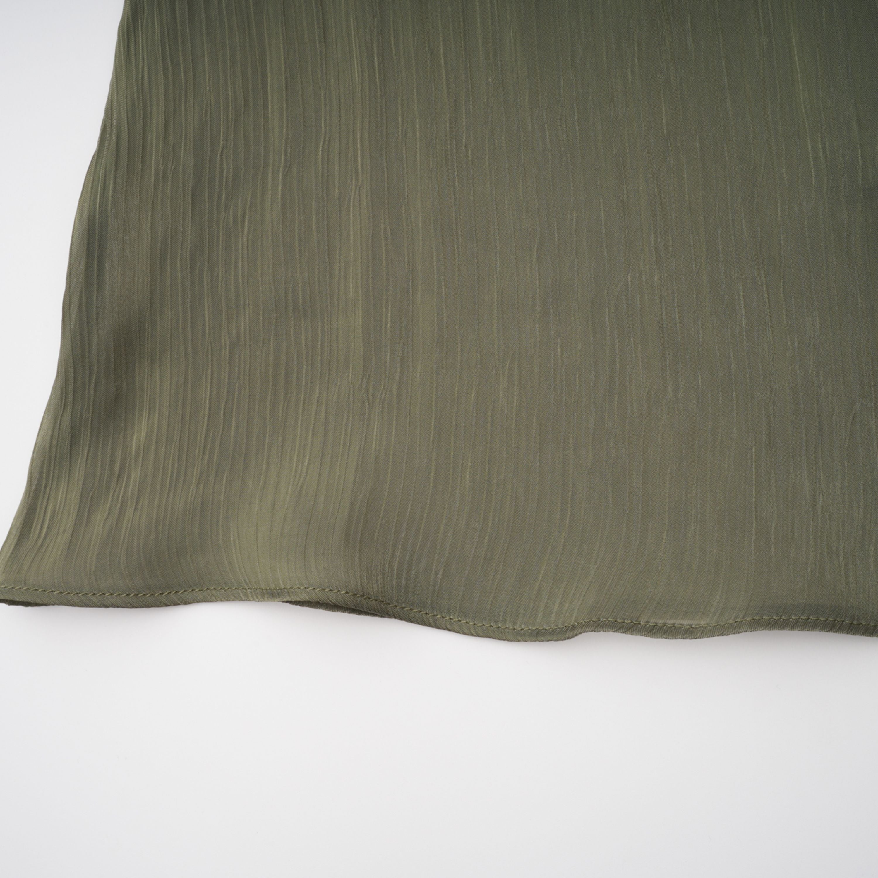 Olive green pleated one-shoulder gown with beaded embellishments and a long draped shoulder cape