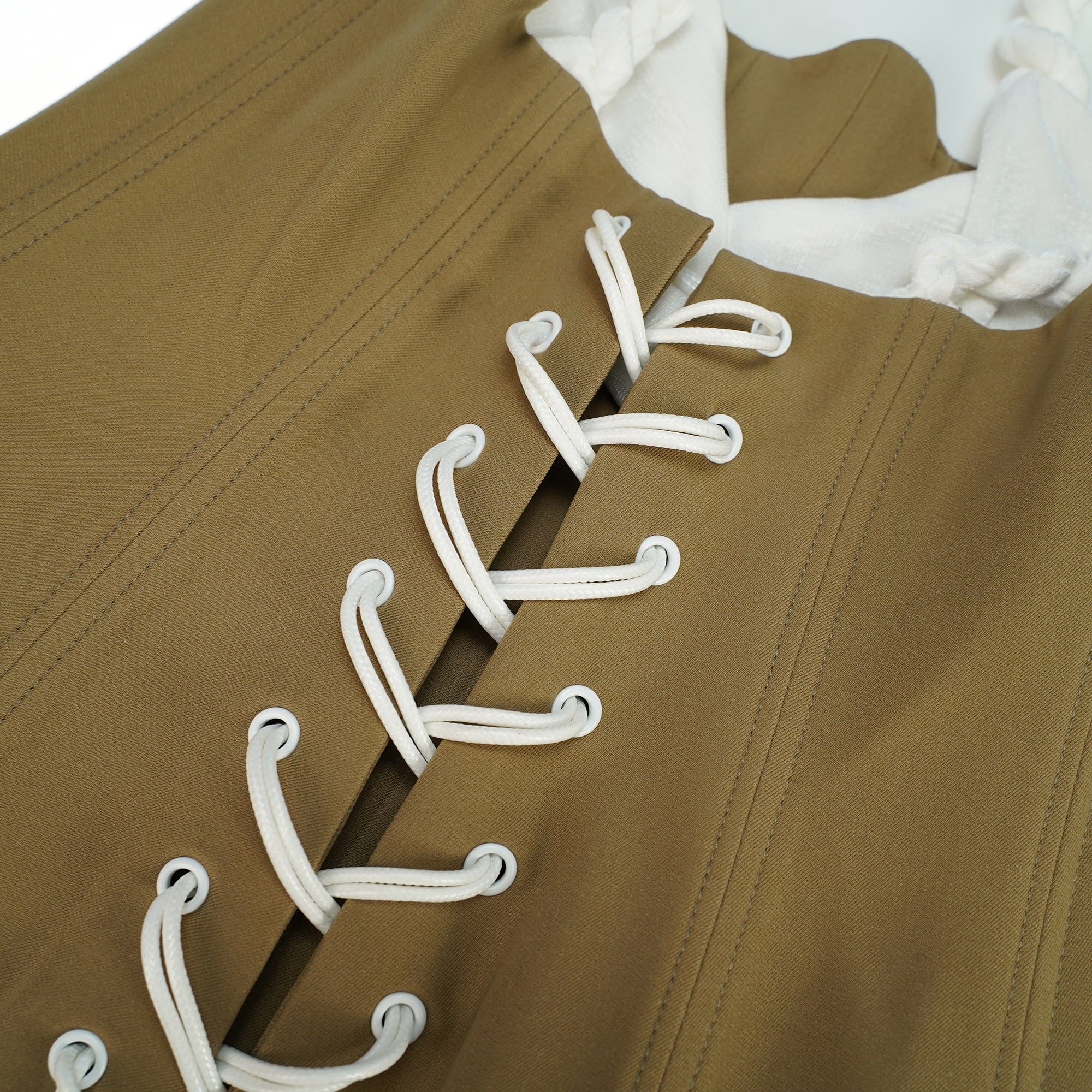 White camisole mini dress featuring a structured tan corset bodice and a draped ruched skirt with drawstring details