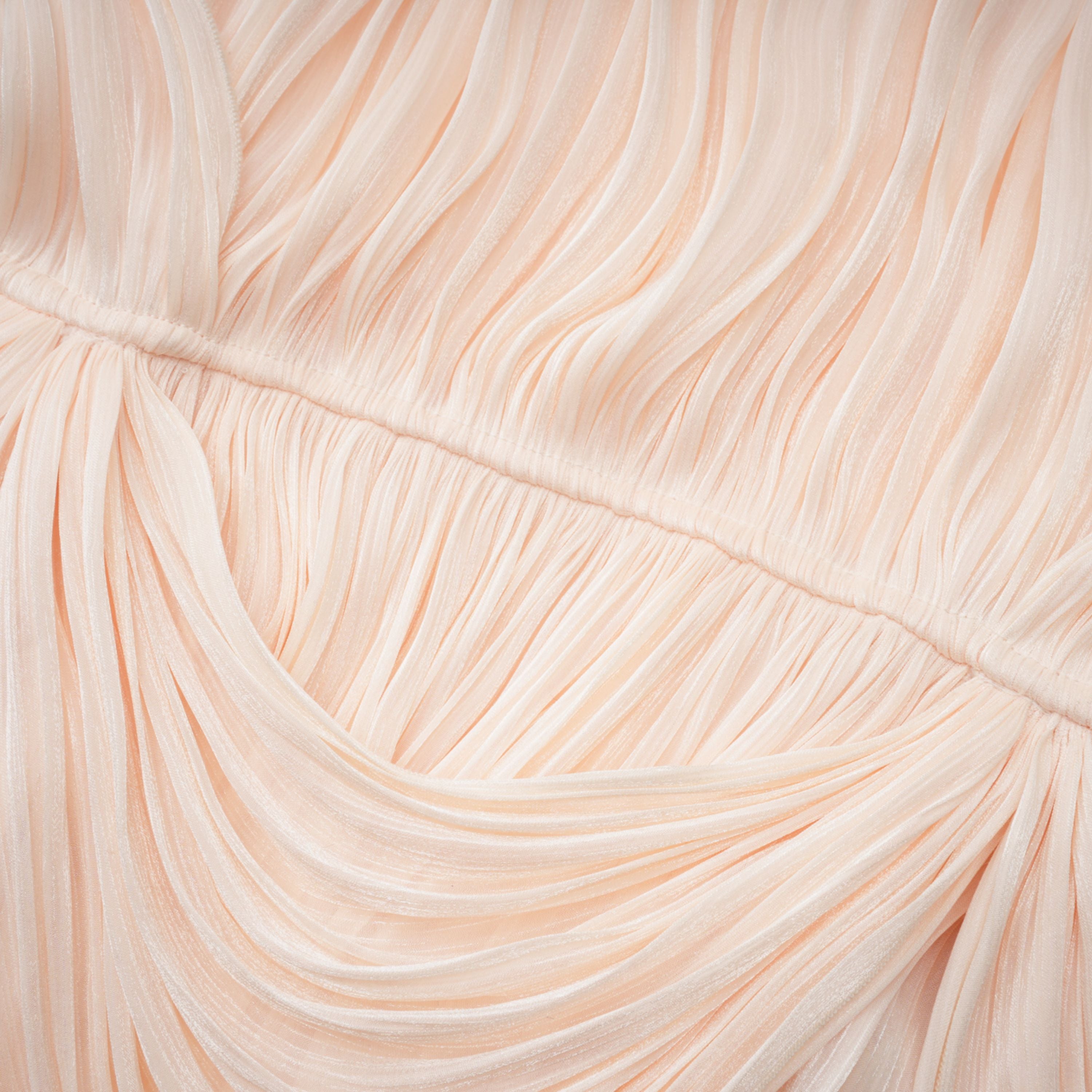 Cream plissé mini dress with a square neckline, structured puff sleeves, and a draped ruffled skirt