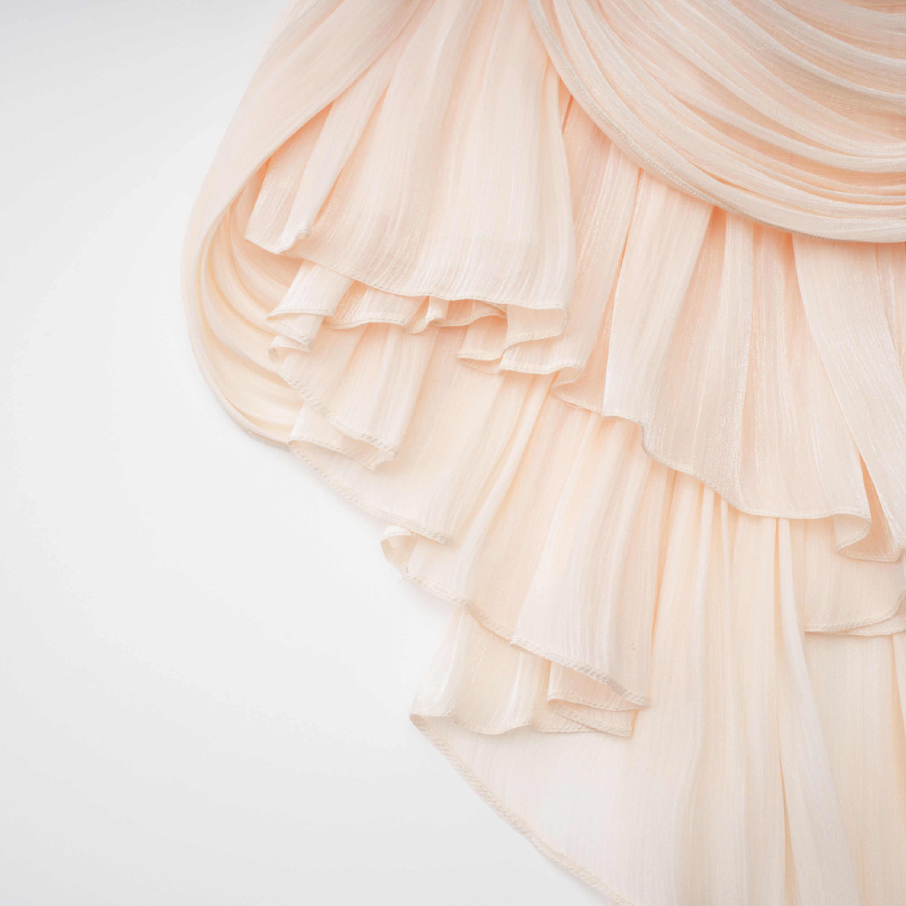 Cream plissé mini dress with a square neckline, structured puff sleeves, and a draped ruffled skirt